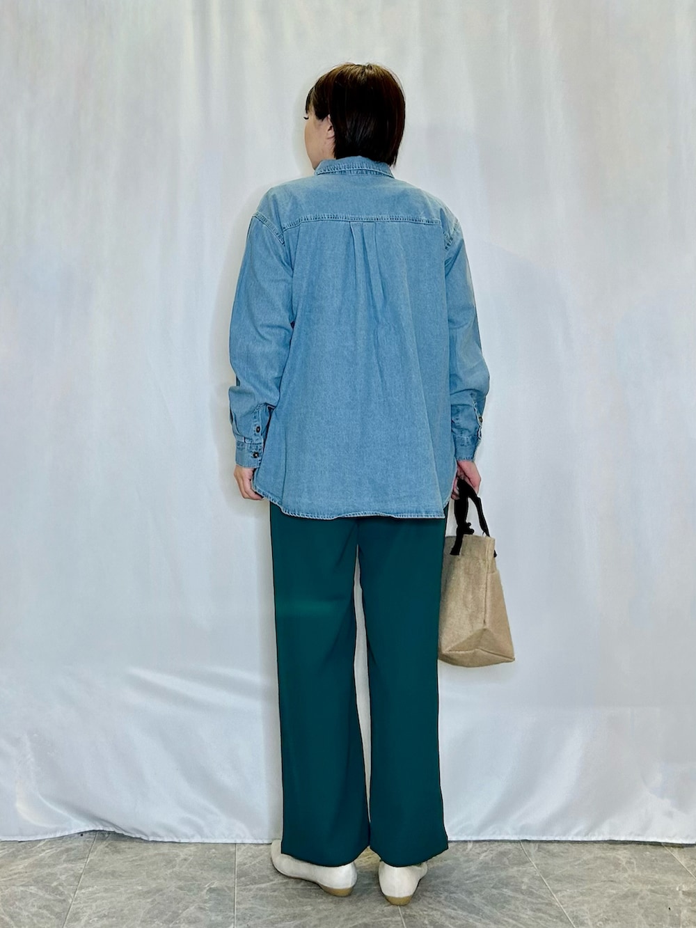 ブラック系のトートバッグ、ゴールド系のその他シューズ、グリーン系のその他パンツを着用したレディースの春コーディネートの3枚目の写真