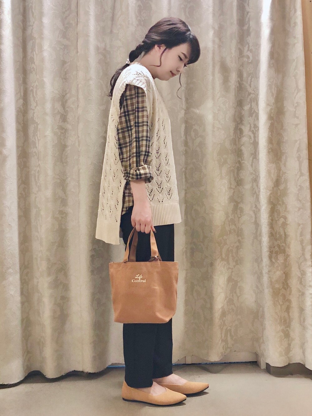 イエロー系のパンプス、ブラック系のその他パンツ、ベージュ系のベストを着用したレディースの秋コーディネートの2枚目の写真