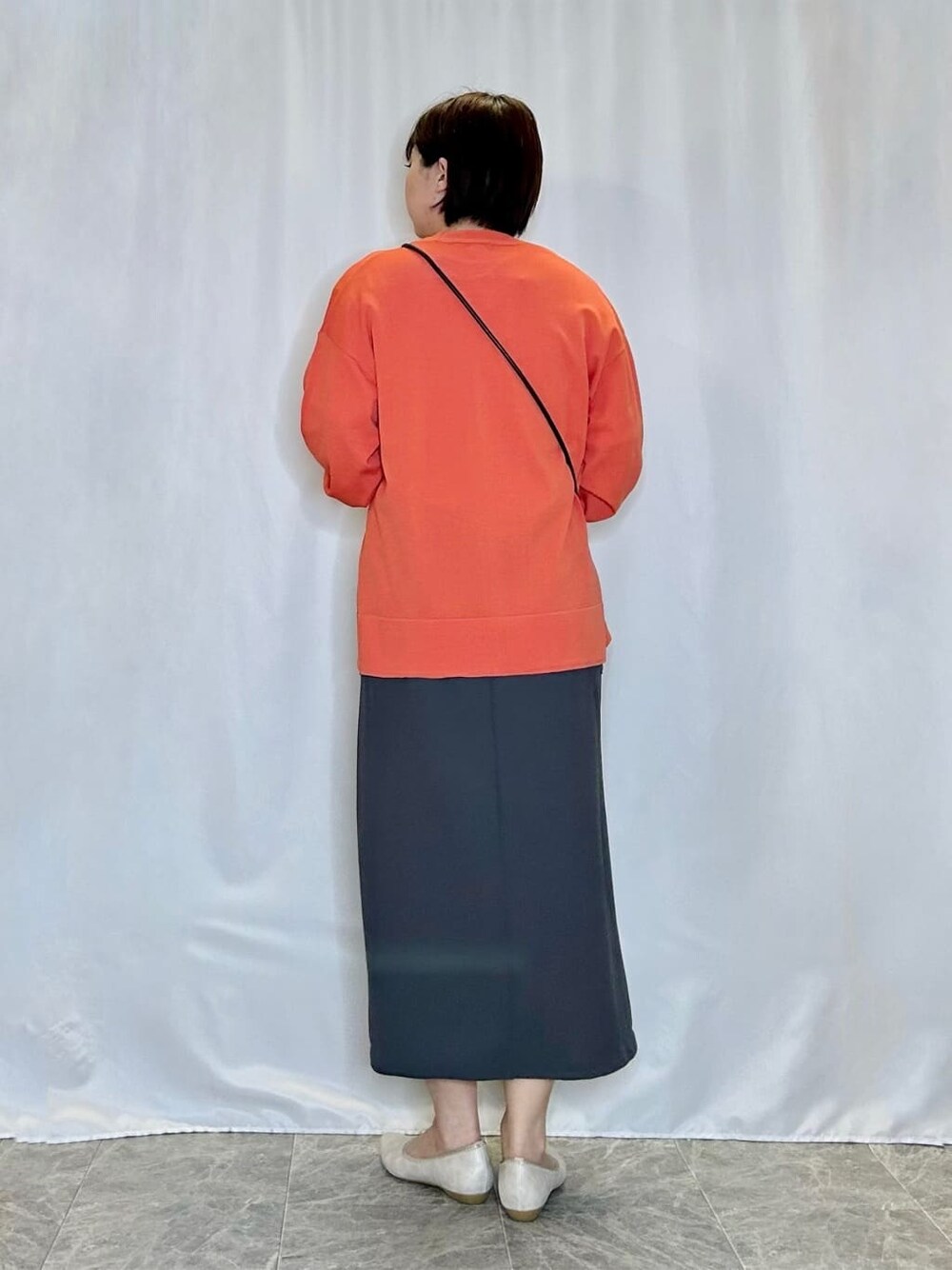 オレンジ系のカーディガン/ボレロ、ホワイト系のTシャツ/カットソー、グレー系のスカートを着用したレディースの春コーディネートの3枚目の写真