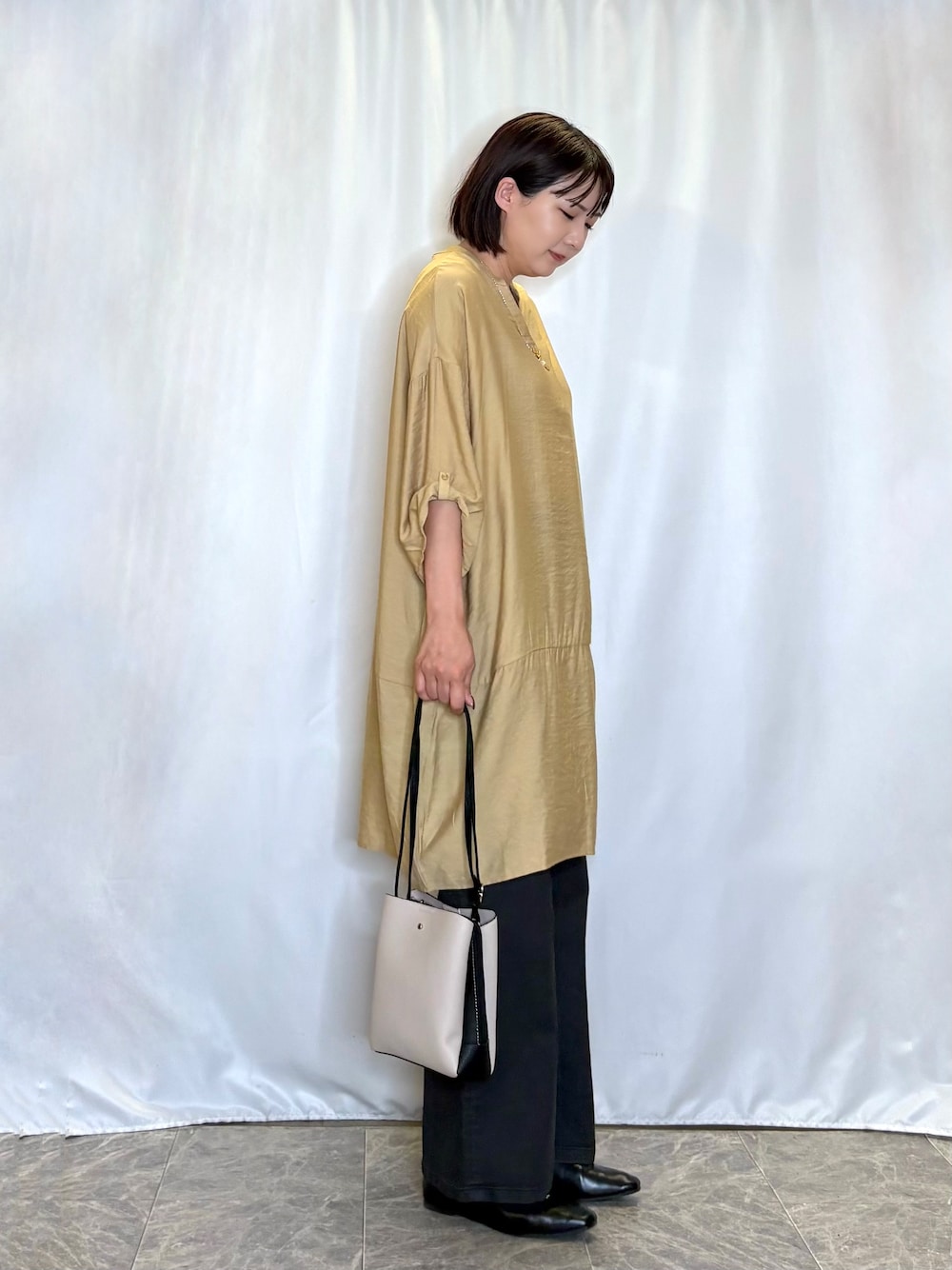 イエロー系のワンピース、ブラック系のデニムパンツ、ベージュ系のショルダーバッグを着用したレディースの夏コーディネートの2枚目の写真