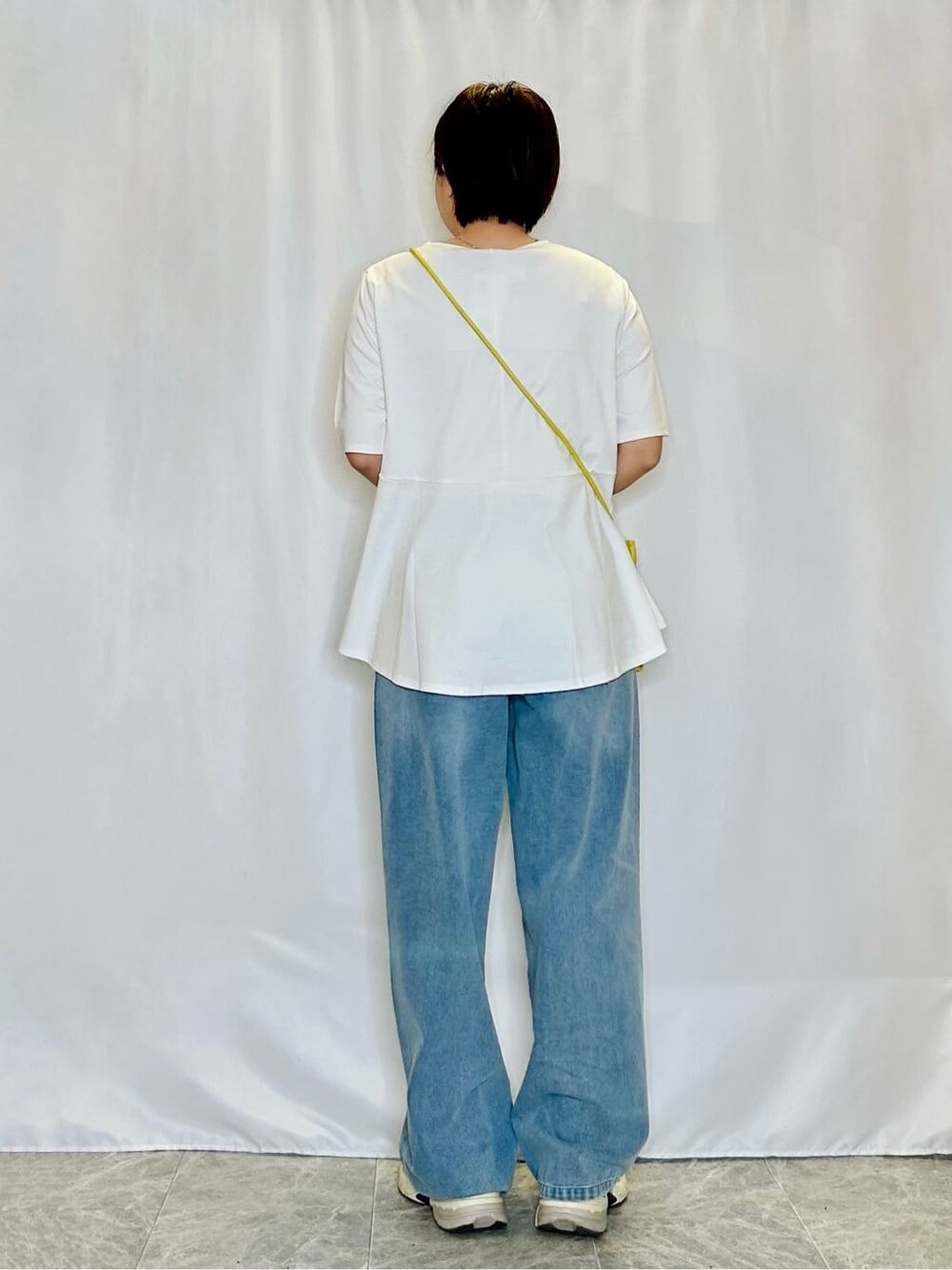 ホワイト系のTシャツ/カットソー、ブルー系のデニムパンツ、イエロー系のショルダーバッグを着用したレディースの春コーディネートの3枚目の写真