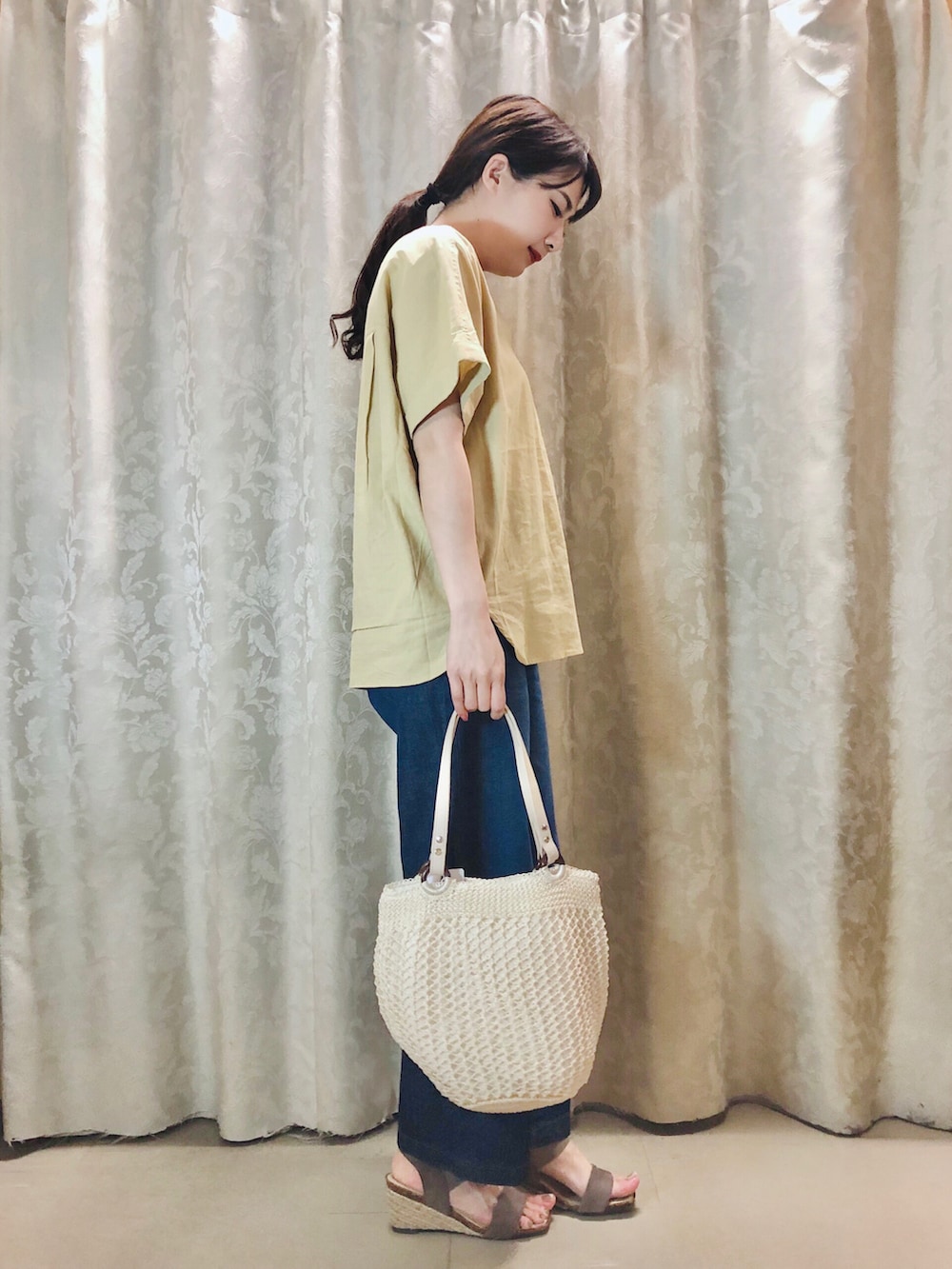 ブルー系のデニムパンツ、イエロー系のシャツ/ブラウス、ブラウン系のサンダルを着用したレディースの春コーディネートの2枚目の写真