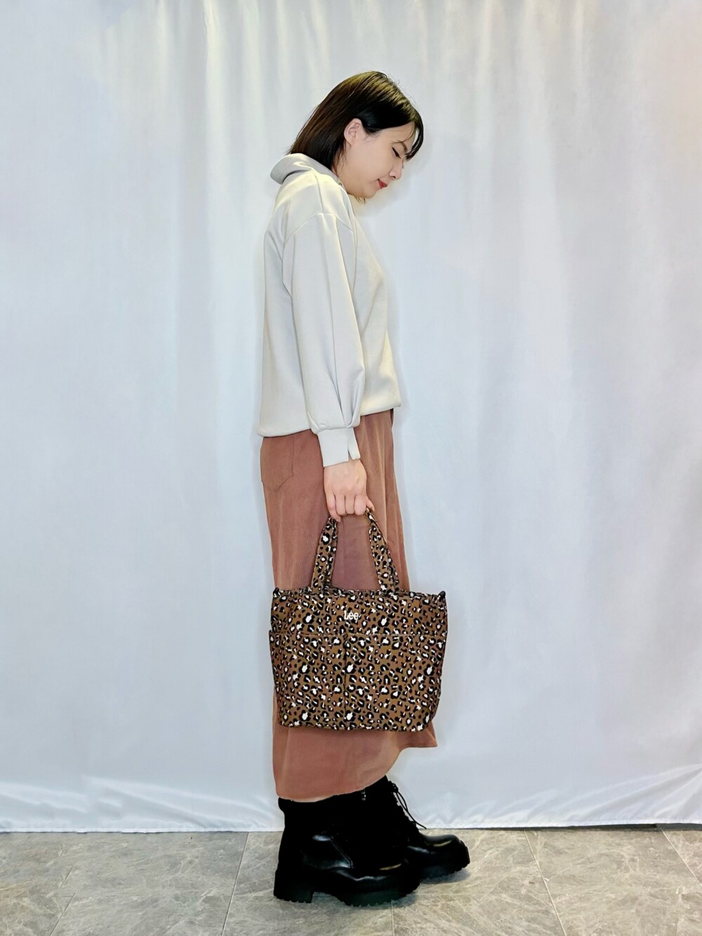 ブラック系のブーツ、グレー系のスウェット、ピンク系のスカートを着用したレディースの秋コーディネートの2枚目の写真