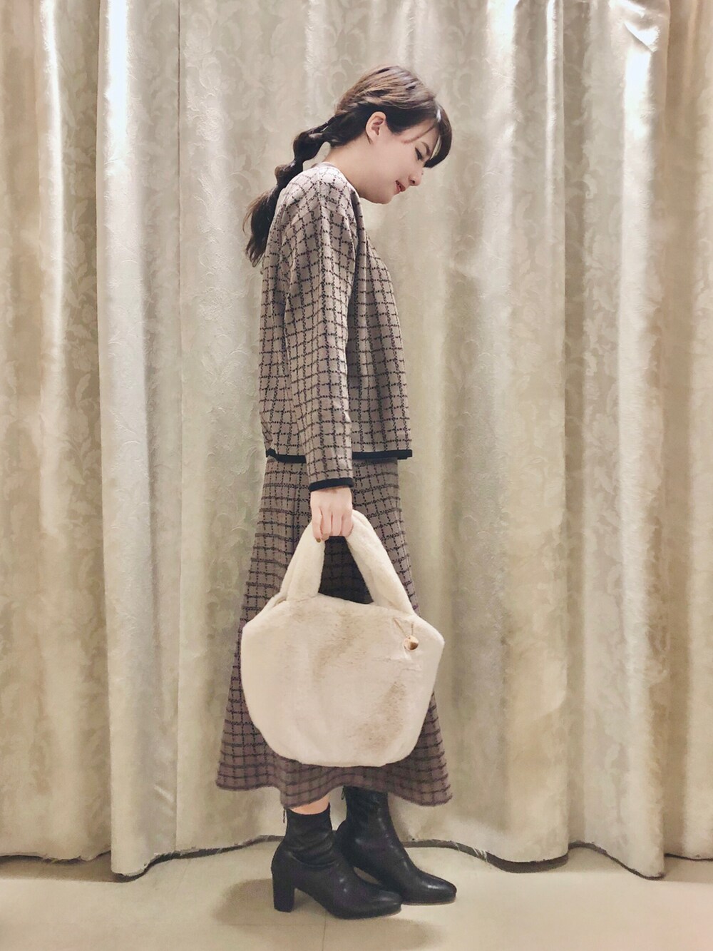 ブラウン系のニット/セーター、ブラウン系のスカート、ブラック系のブーツを着用したレディースの冬コーディネートの2枚目の写真