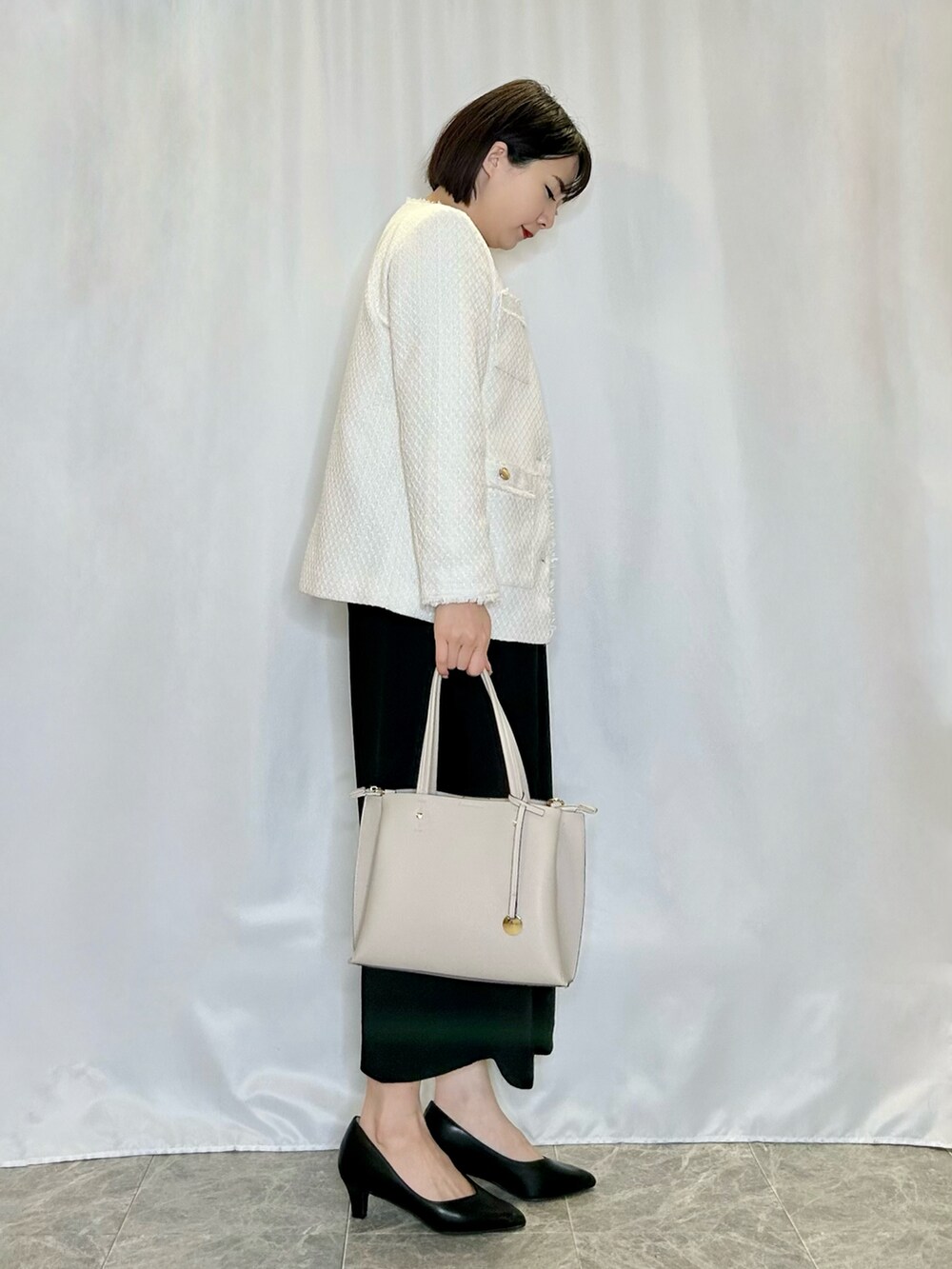 ブラック系のパンプス、グレー系のトートバッグ、ベージュ系のノーカラージャケットを着用したレディースの冬コーディネートの2枚目の写真