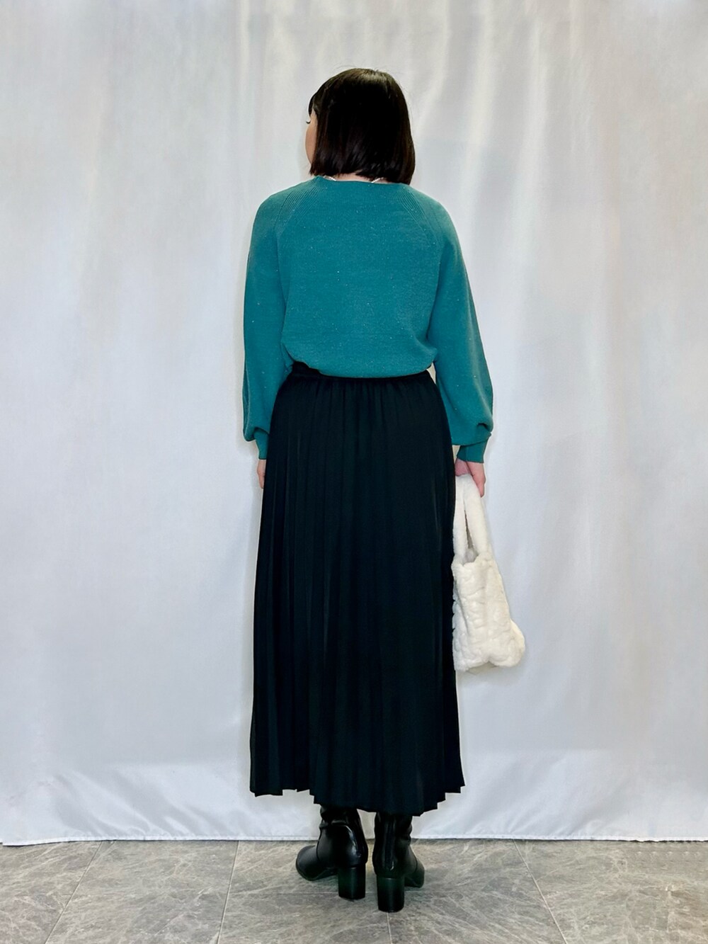 ベージュ系のトートバッグ、ブラック系のブーツ、ブラック系のスカートを着用したレディースの冬コーディネートの3枚目の写真