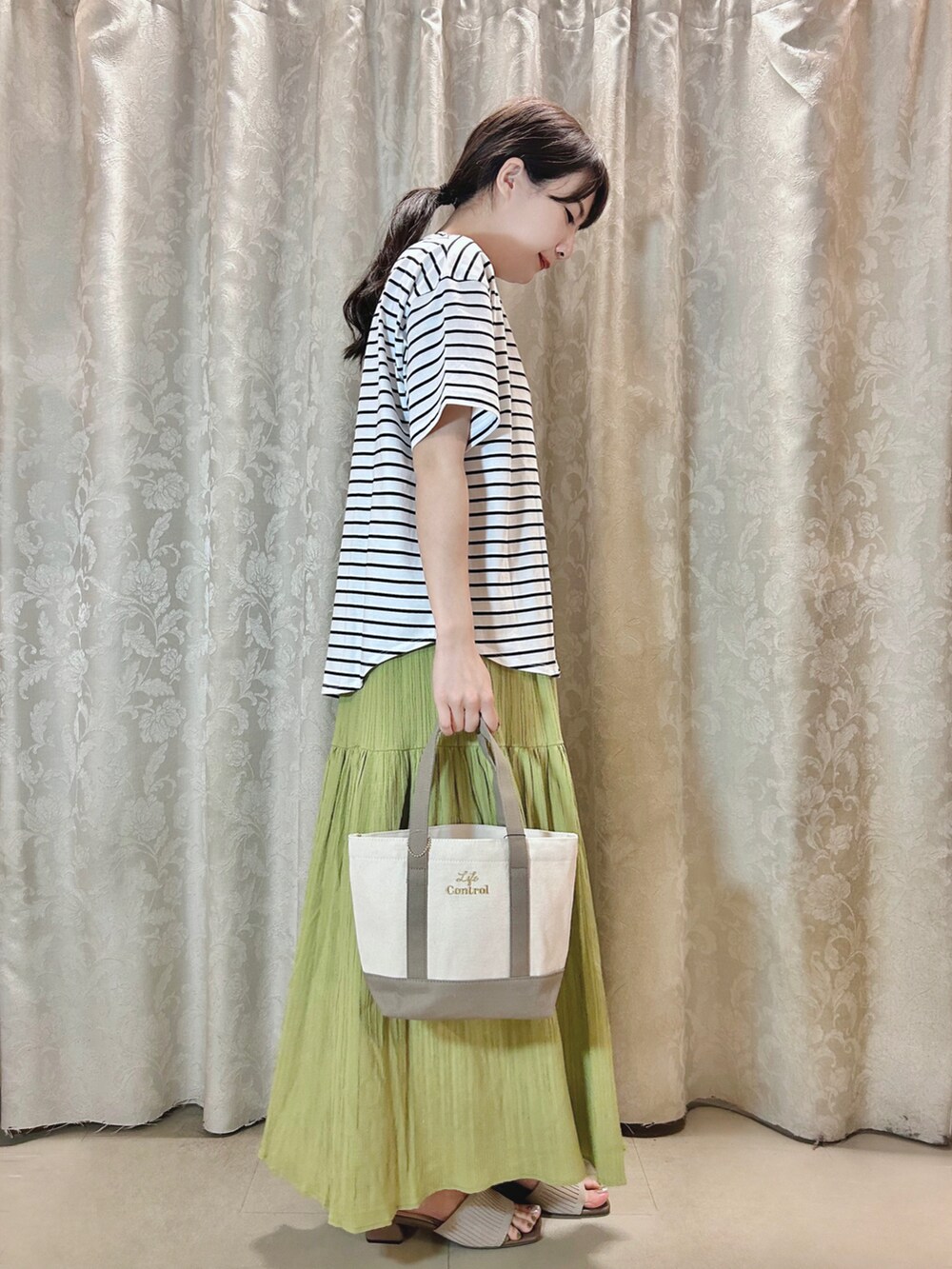 ホワイト系のTシャツ/カットソー、ブラウン系のトートバッグ、ベージュ系のサンダルを着用したレディースの春コーディネートの2枚目の写真