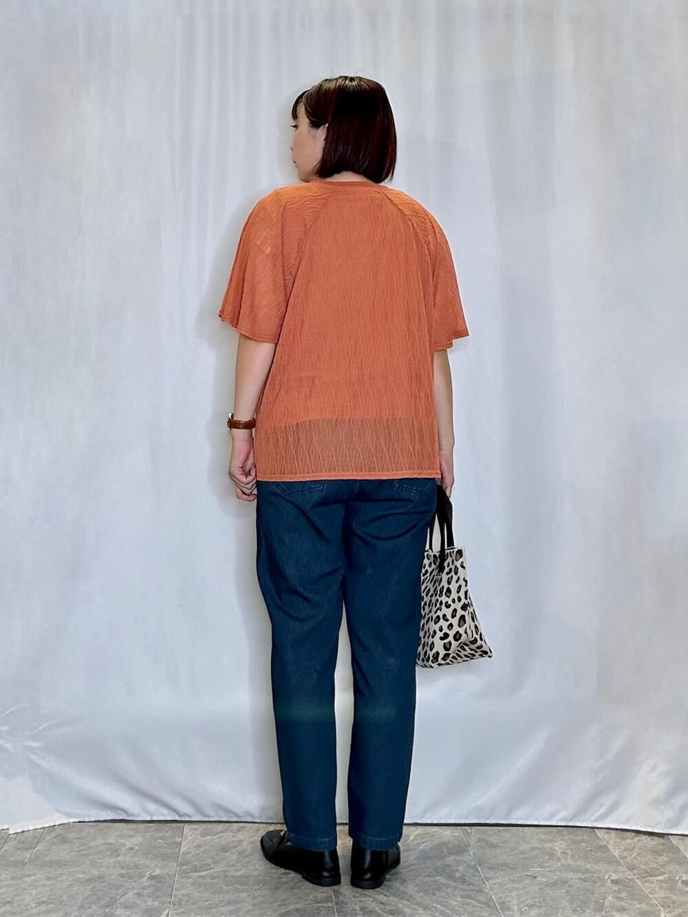 レッド系のTシャツ/カットソー、ブルー系のデニムパンツ、ブラック系のその他シューズを着用したレディースの秋コーディネートの3枚目の写真