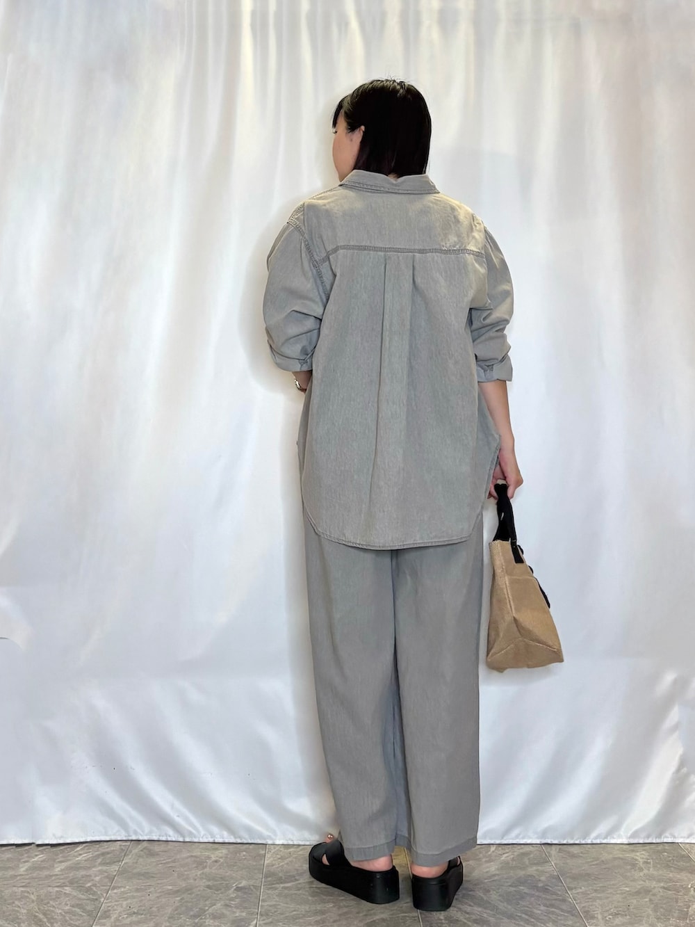 グレー系のデニムパンツ、グレー系のシャツ/ブラウス、ブラック系のトートバッグを着用したレディースの春コーディネートの3枚目の写真