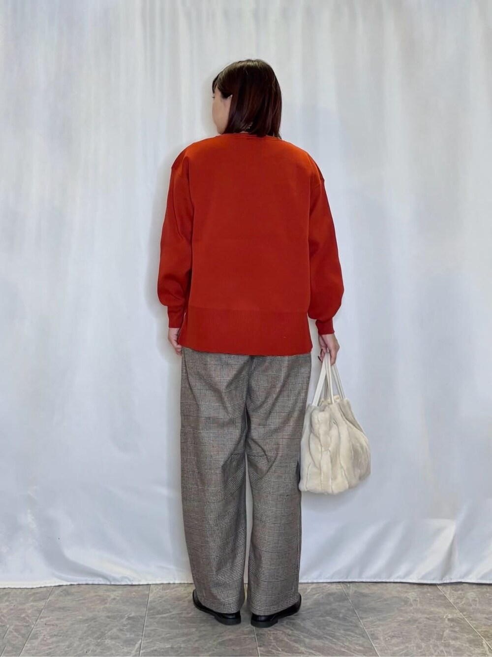 レッド系のニット/セーター、ベージュ系のその他パンツ、ブラック系のその他シューズを着用したレディースの秋コーディネートの3枚目の写真