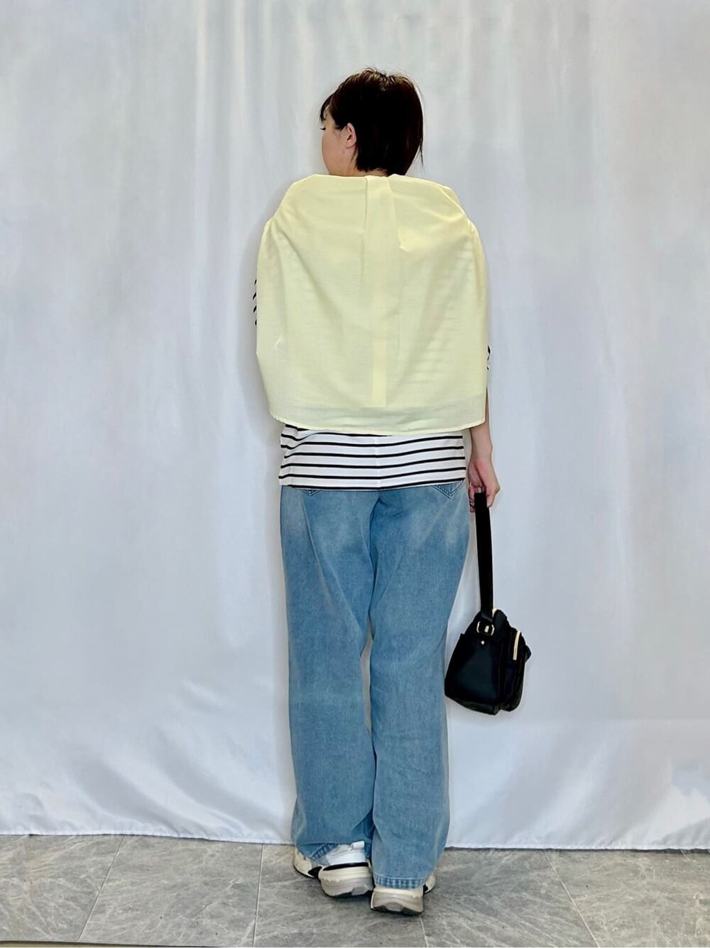 イエロー系のシャツ/ブラウス、ブラック系のTシャツ/カットソー、ブルー系のデニムパンツを着用したレディースの春コーディネートの3枚目の写真