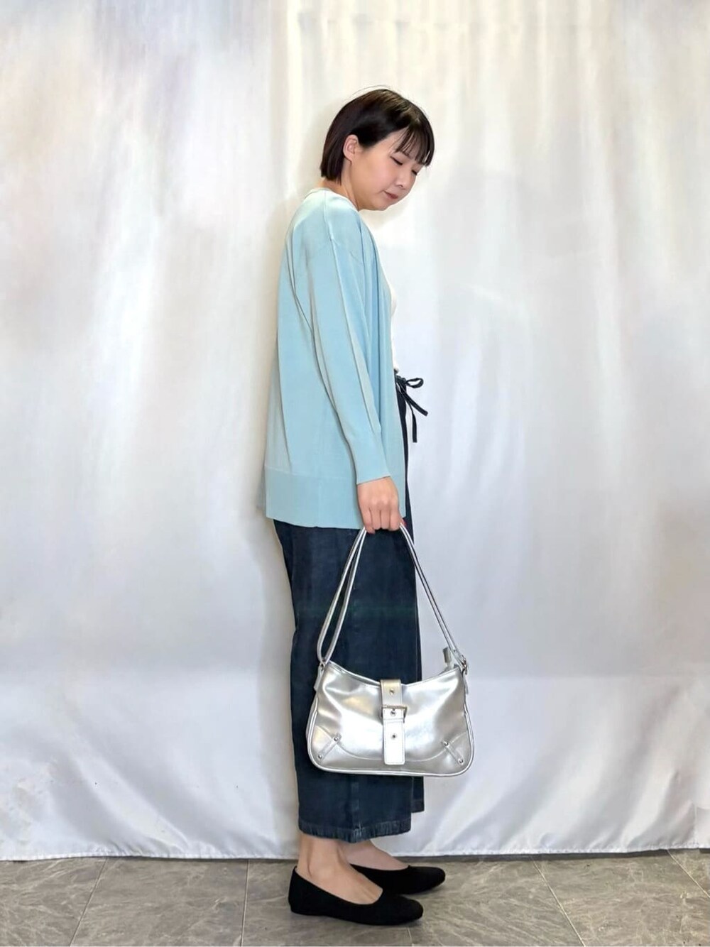 ブルー系のデニムパンツ、ブラック系のワンピース、グリーン系のカーディガン/ボレロを着用したレディースの春コーディネートの2枚目の写真