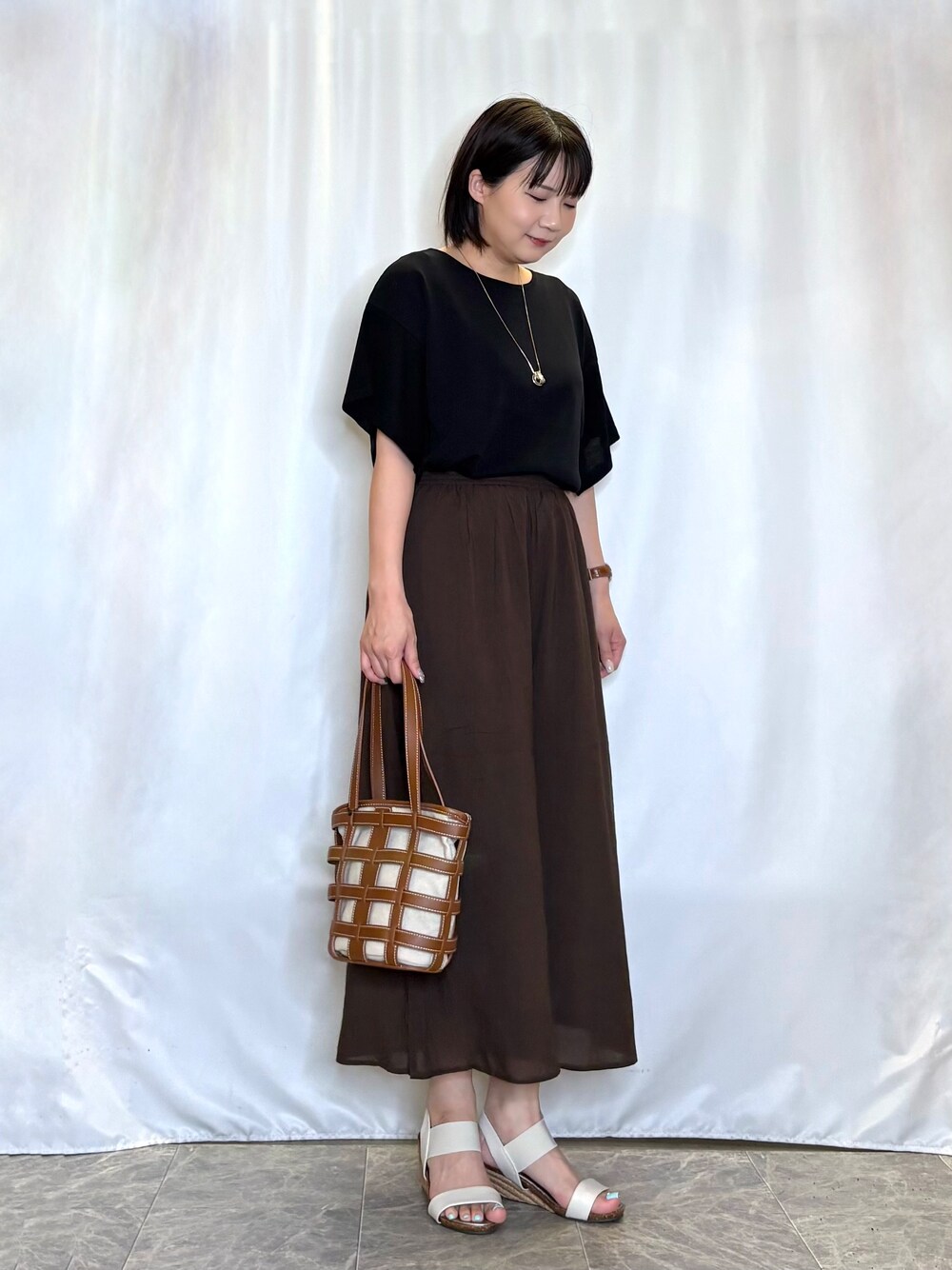 ブラック系のニット/セーター、ブラウン系のその他パンツ、ホワイト系のサンダルを着用したレディースの夏コーディネートの3枚目の写真