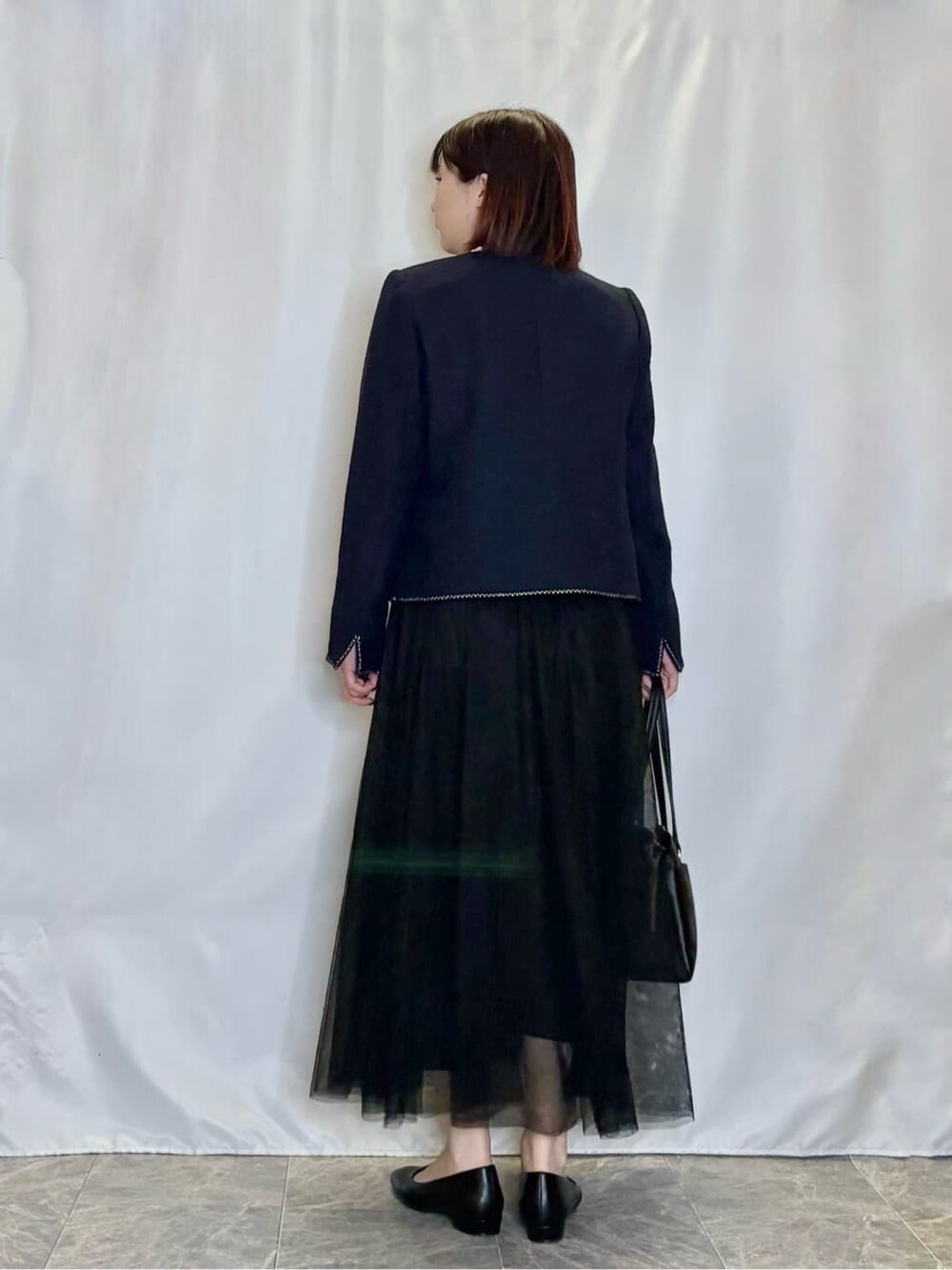 ブルー系のノーカラージャケット、ホワイト系のシャツ/ブラウス、ブラック系のスカートを着用したレディースの春コーディネートの3枚目の写真