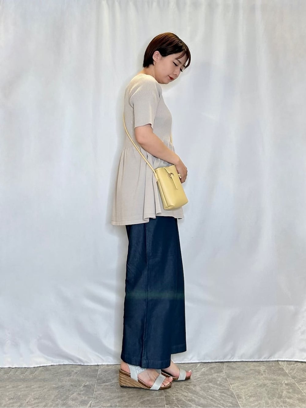 ベージュ系のニット/セーター、ブルー系のその他パンツ、シルバー系のサンダルを着用したレディースの夏コーディネートの2枚目の写真
