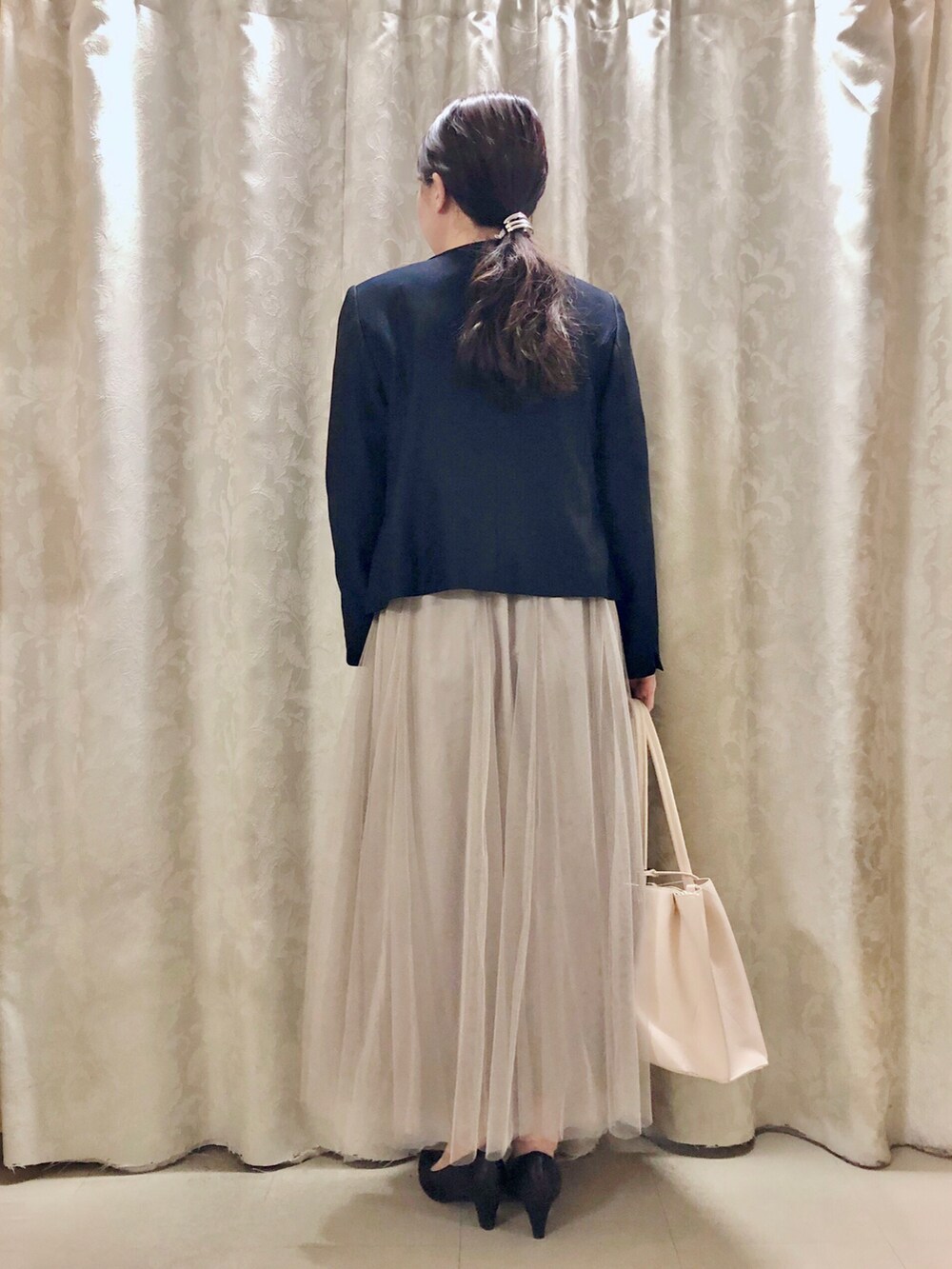 ホワイト系のトートバッグ、ブラック系のパンプス、ブルー系のノーカラージャケットを着用したレディースの冬コーディネートの3枚目の写真