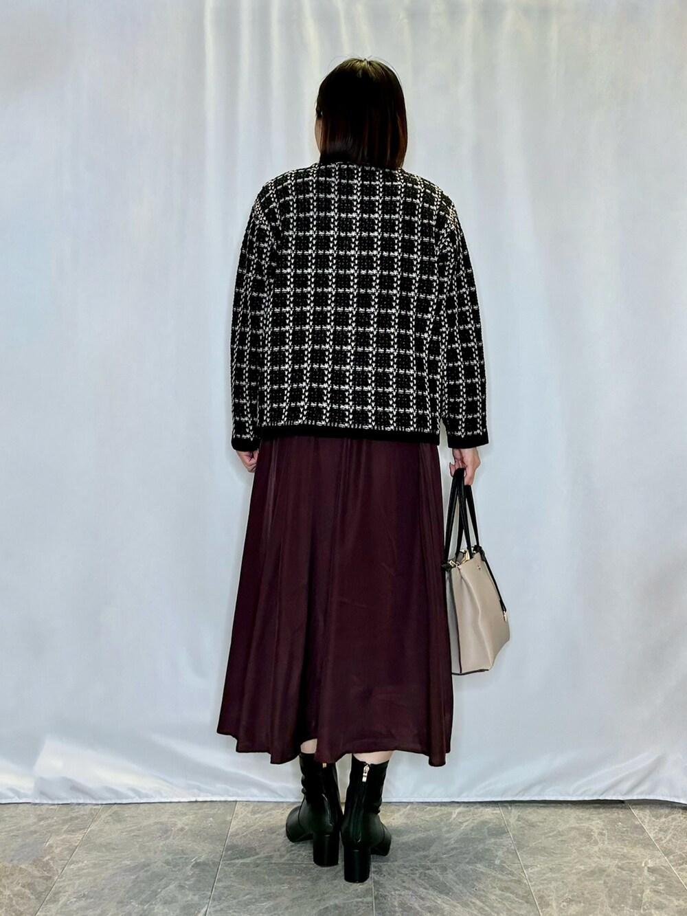 ブラウン系のスカート、ベージュ系のトートバッグ、ブラック系のブーツを着用したレディースの秋コーディネートの3枚目の写真