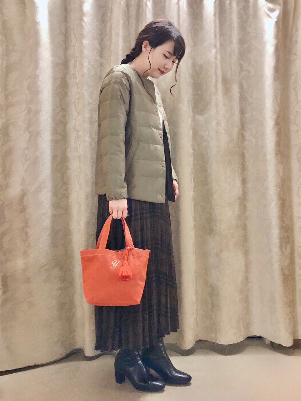 グリーン系のダウンジャケット/コート、ブラウン系のスカート、ブラック系のブーツを着用したレディースの秋コーディネートの2枚目の写真