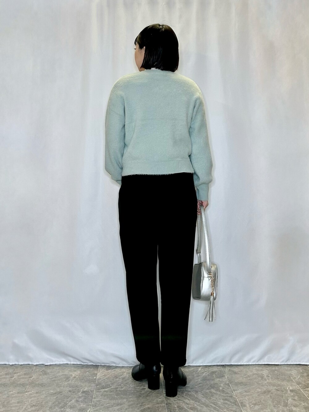 シルバー系のショルダーバッグ、ブラック系のブーツ、グリーン系のカーディガン/ボレロを着用したレディースの冬コーディネートの3枚目の写真