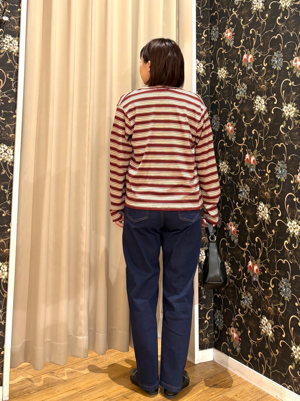 ブルー系のデニムパンツ、ブラック系のショルダーバッグ、ゴールド系のネックレスを着用したレディースの秋コーディネートの3枚目の写真
