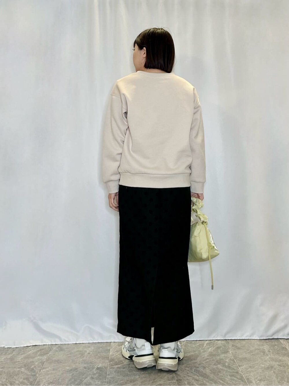 ベージュ系のTシャツ/カットソー、グレー系のスカート、イエロー系のショルダーバッグを着用したレディースの冬コーディネートの3枚目の写真