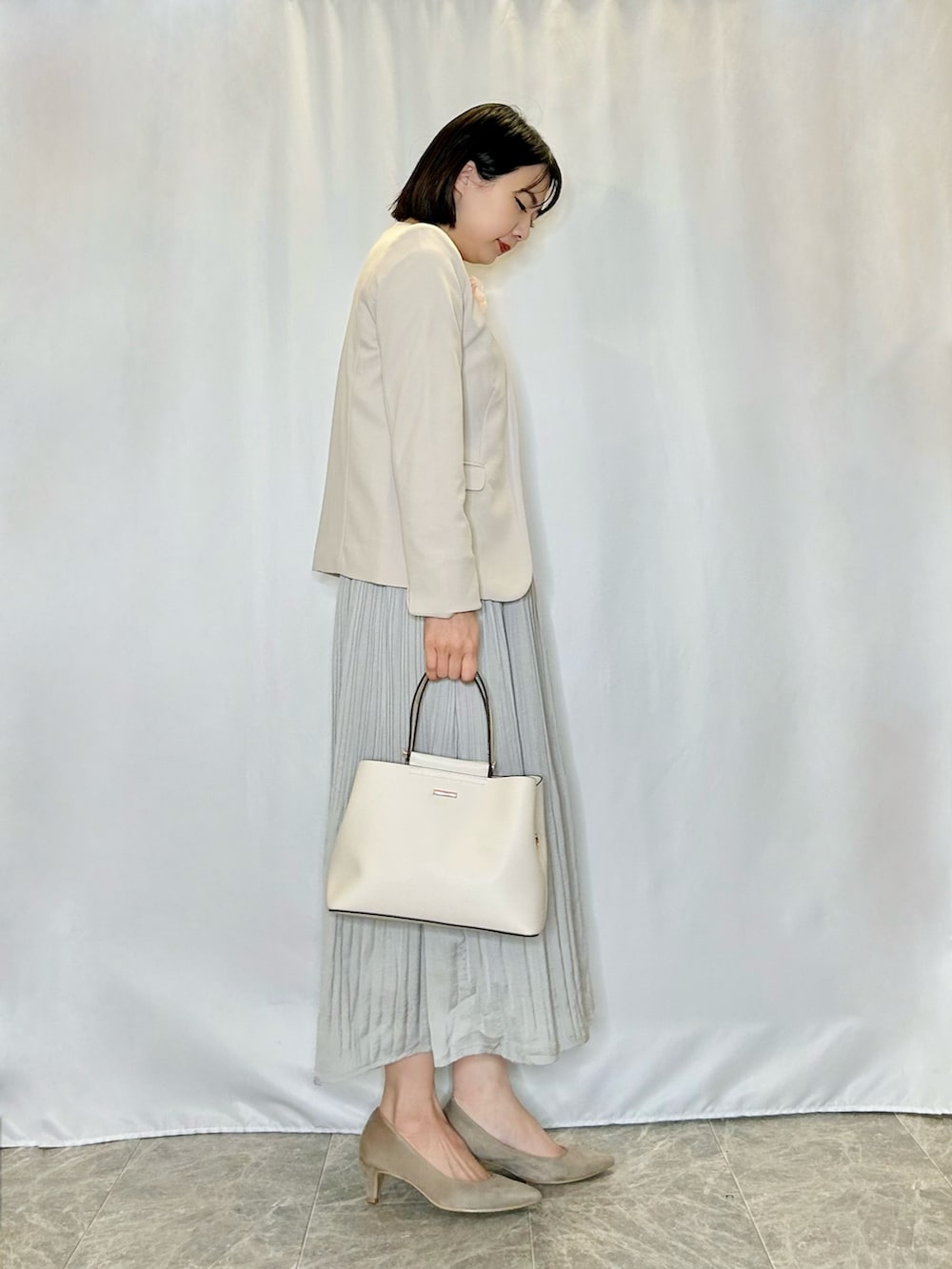 ベージュ系のパンプス、グレー系のスカート、ホワイト系のトートバッグを着用したレディースの冬コーディネートの2枚目の写真