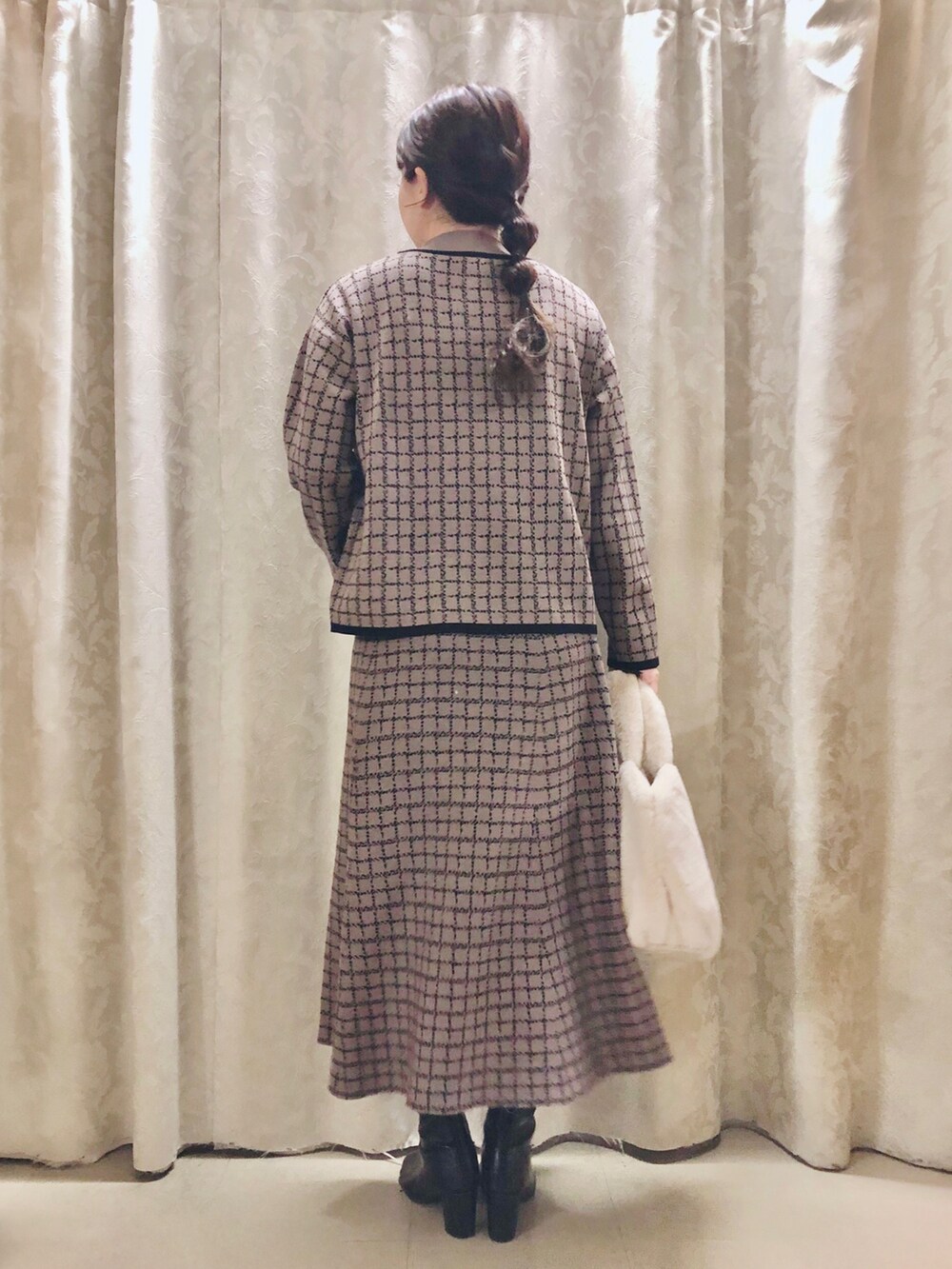 ブラウン系のニット/セーター、ブラウン系のスカート、ブラック系のブーツを着用したレディースの冬コーディネートの3枚目の写真