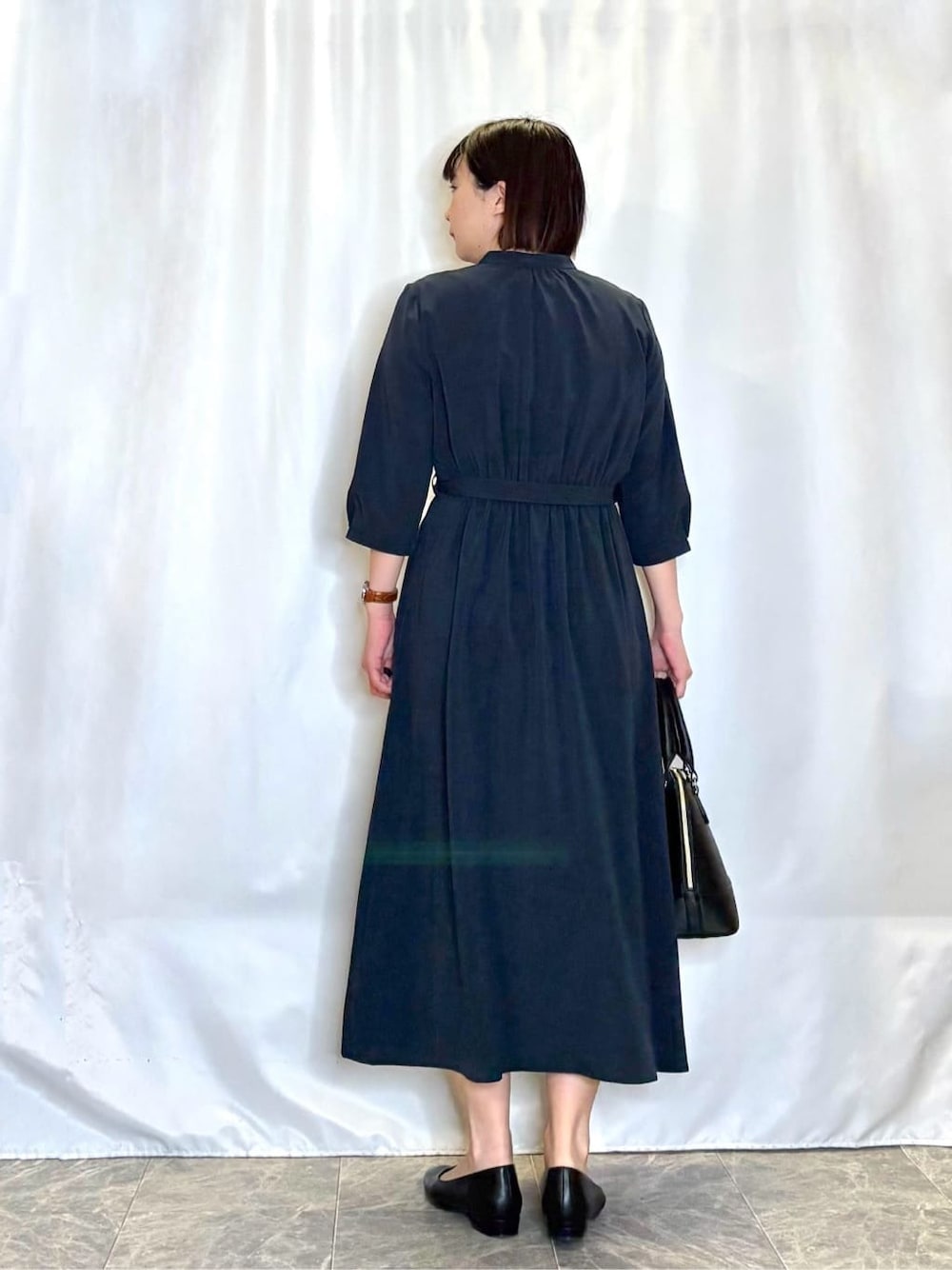 ブラック系のトートバッグ、ブラック系のパンプス、ブルー系のワンピースを着用したレディースの春コーディネートの3枚目の写真