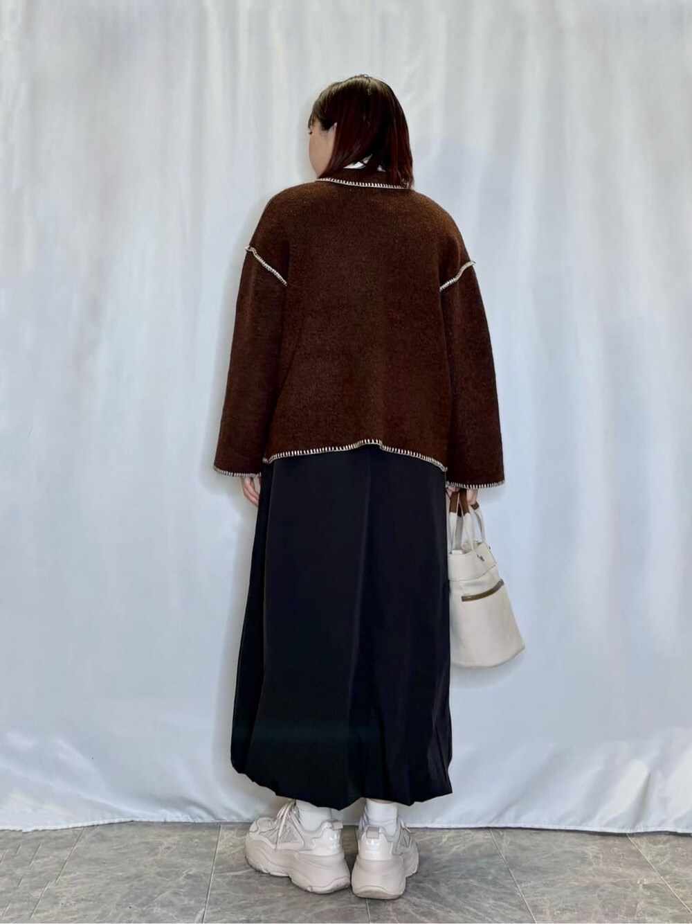 ブラウン系のカーディガン/ボレロ、ホワイト系のTシャツ/カットソー、ブラック系のスカートを着用したレディースの秋コーディネートの3枚目の写真