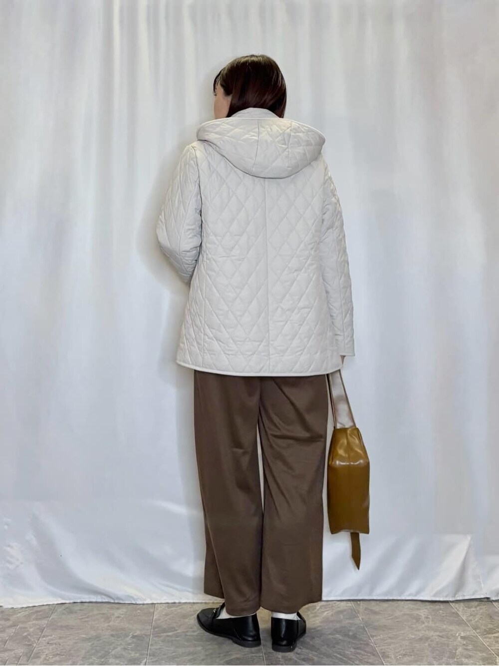 ベージュ系のその他アウター、レッド系のニット/セーター、ブラウン系のその他パンツを着用したレディースの秋コーディネートの3枚目の写真