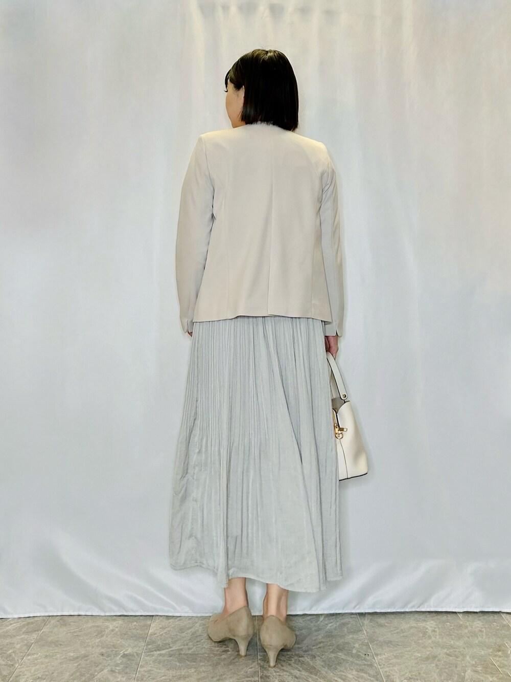 ベージュ系のパンプス、グレー系のスカート、ホワイト系のトートバッグを着用したレディースの冬コーディネートの3枚目の写真