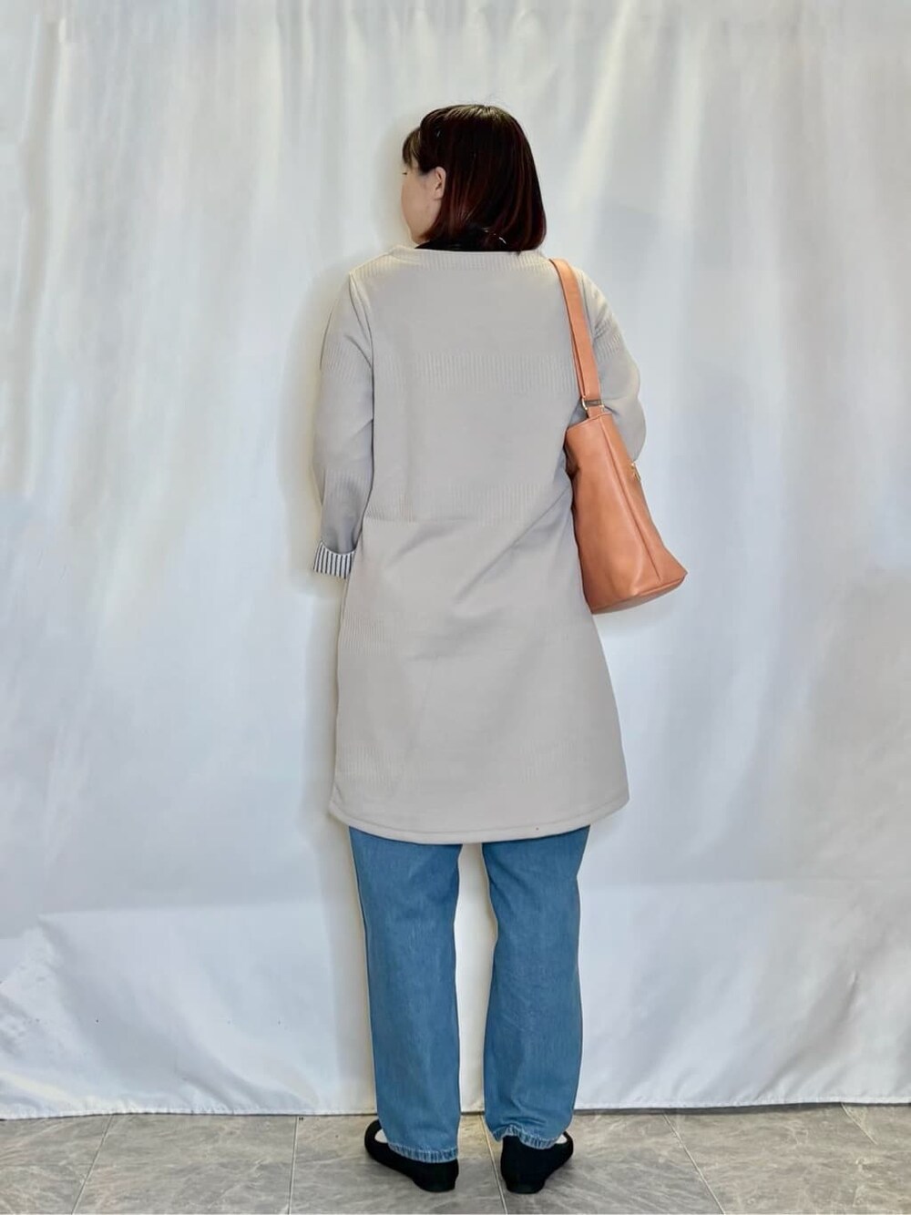 ベージュ系のチュニック、ブラック系のTシャツ/カットソー、ブルー系のデニムパンツを着用したレディースの冬コーディネートの3枚目の写真