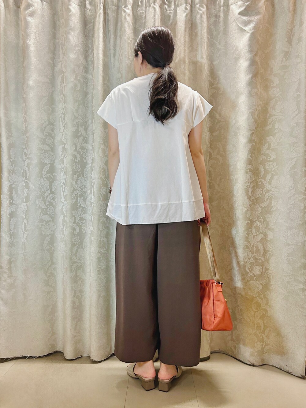 ベージュ系のサンダル、オレンジ系のショルダーバッグ、ホワイト系のTシャツ/カットソーを着用したレディースの春コーディネートの3枚目の写真