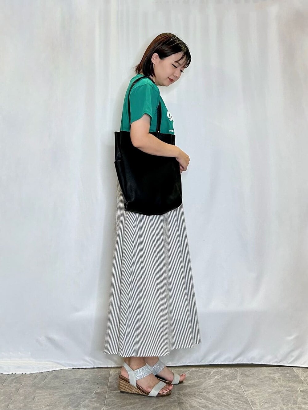 グリーン系のTシャツ/カットソー、グレー系のスカート、シルバー系のサンダルを着用したレディースの夏コーディネートの2枚目の写真