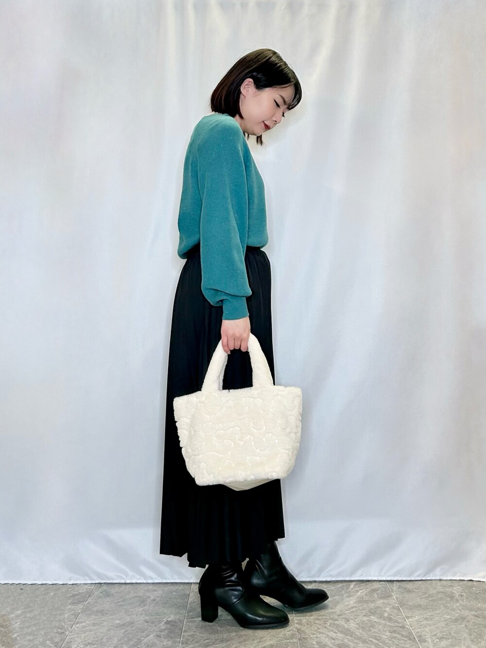 ベージュ系のトートバッグ、ブラック系のブーツ、ブラック系のスカートを着用したレディースの冬コーディネートの2枚目の写真