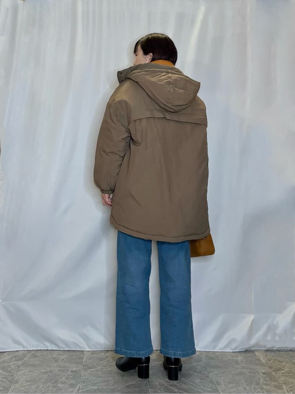 ブラウン系のその他アウター、ホワイト系のニット/セーター、ブルー系のデニムパンツを着用したレディースの冬コーディネートの3枚目の写真