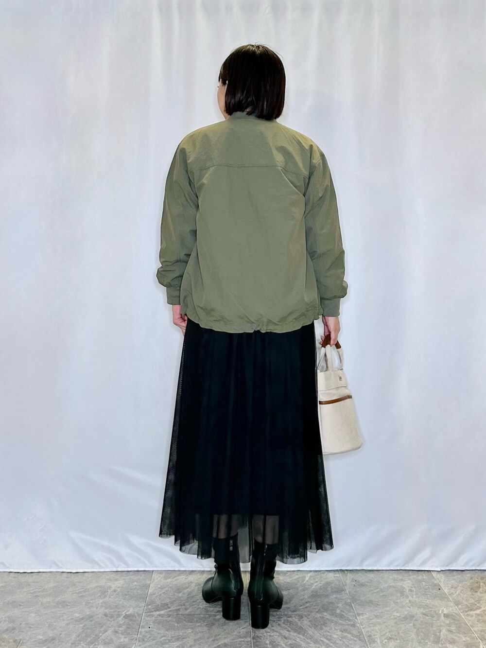 ベージュ系のトートバッグ、ブラック系のブーツ、ブラック系のスカートを着用したレディースの秋コーディネートの3枚目の写真