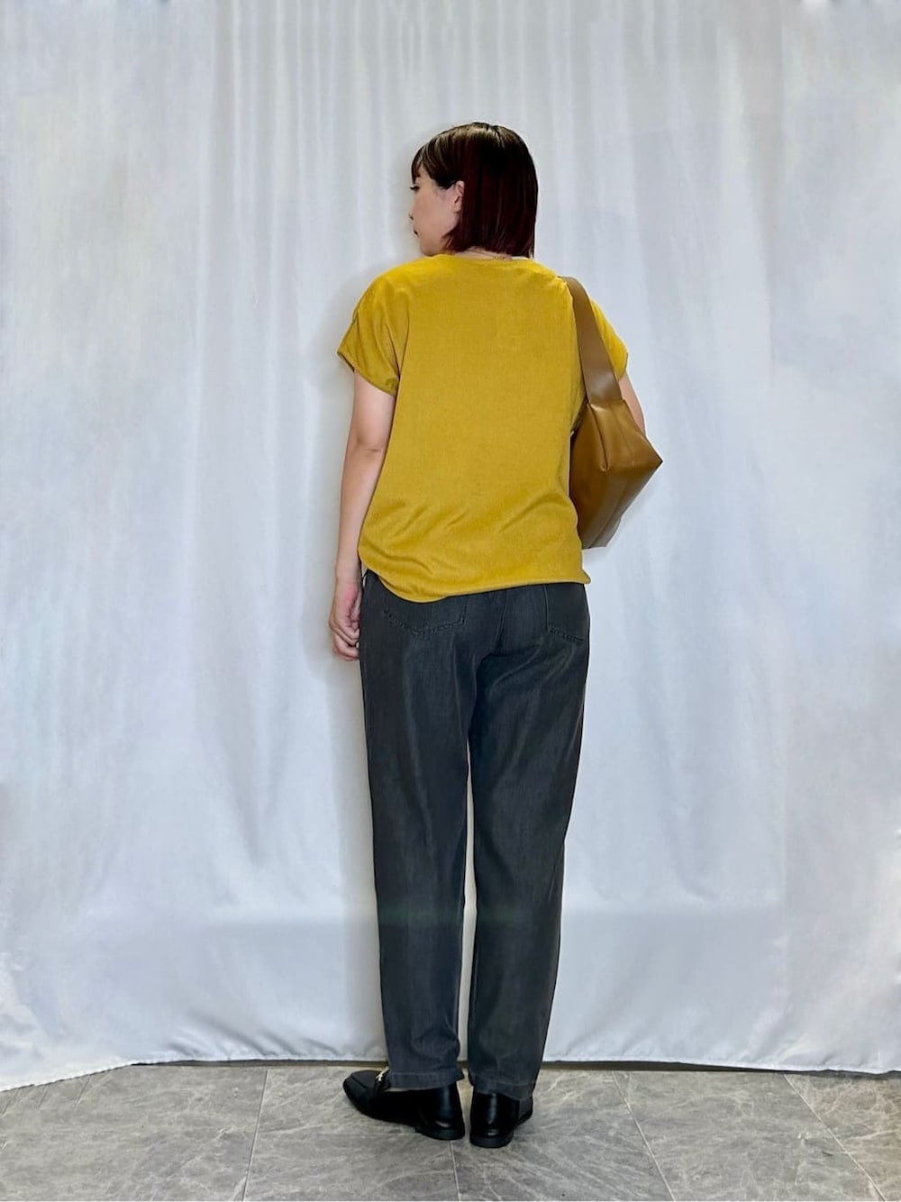 イエロー系のTシャツ/カットソー、グレー系のデニムパンツ、ブラック系のその他シューズを着用したレディースの秋コーディネートの3枚目の写真