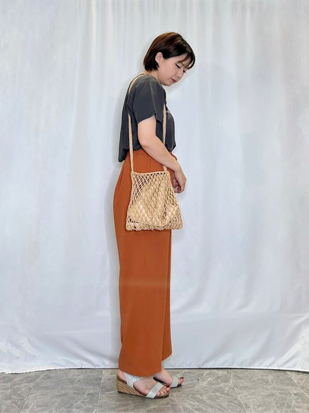 グレー系のTシャツ/カットソー、オレンジ系のその他パンツ、シルバー系のサンダルを着用したレディースの夏コーディネートの2枚目の写真