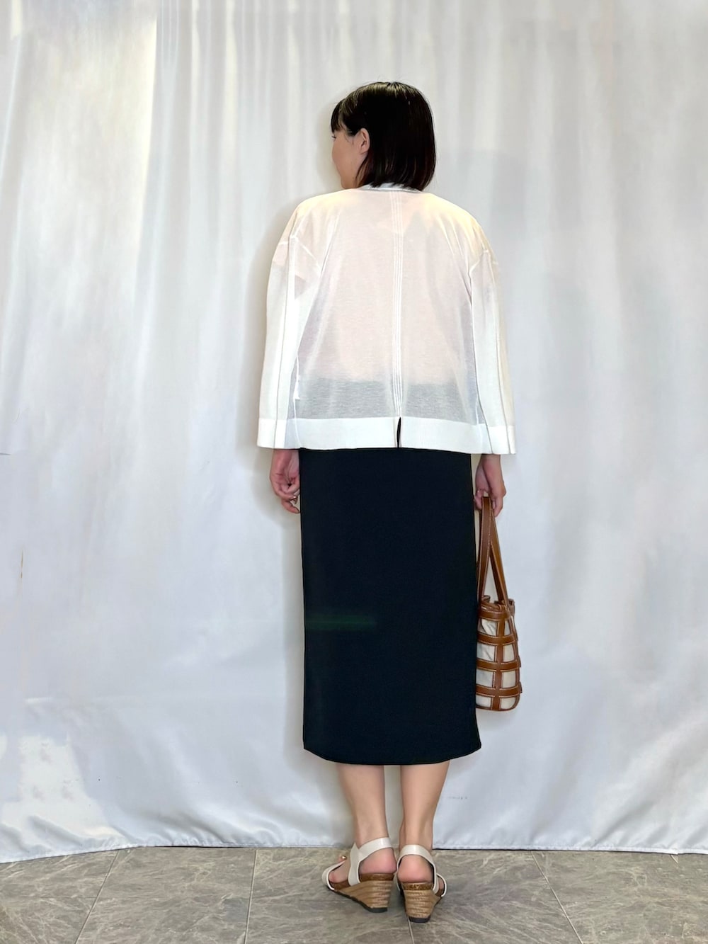 ホワイト系のカーディガン/ボレロ、オレンジ系のTシャツ/カットソー、ブルー系のスカートを着用したレディースの夏コーディネートの3枚目の写真
