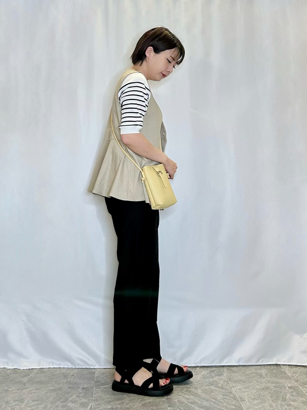 ブラック系のその他パンツ、ブラック系のサンダル、イエロー系のショルダーバッグを着用したレディースの春コーディネートの2枚目の写真