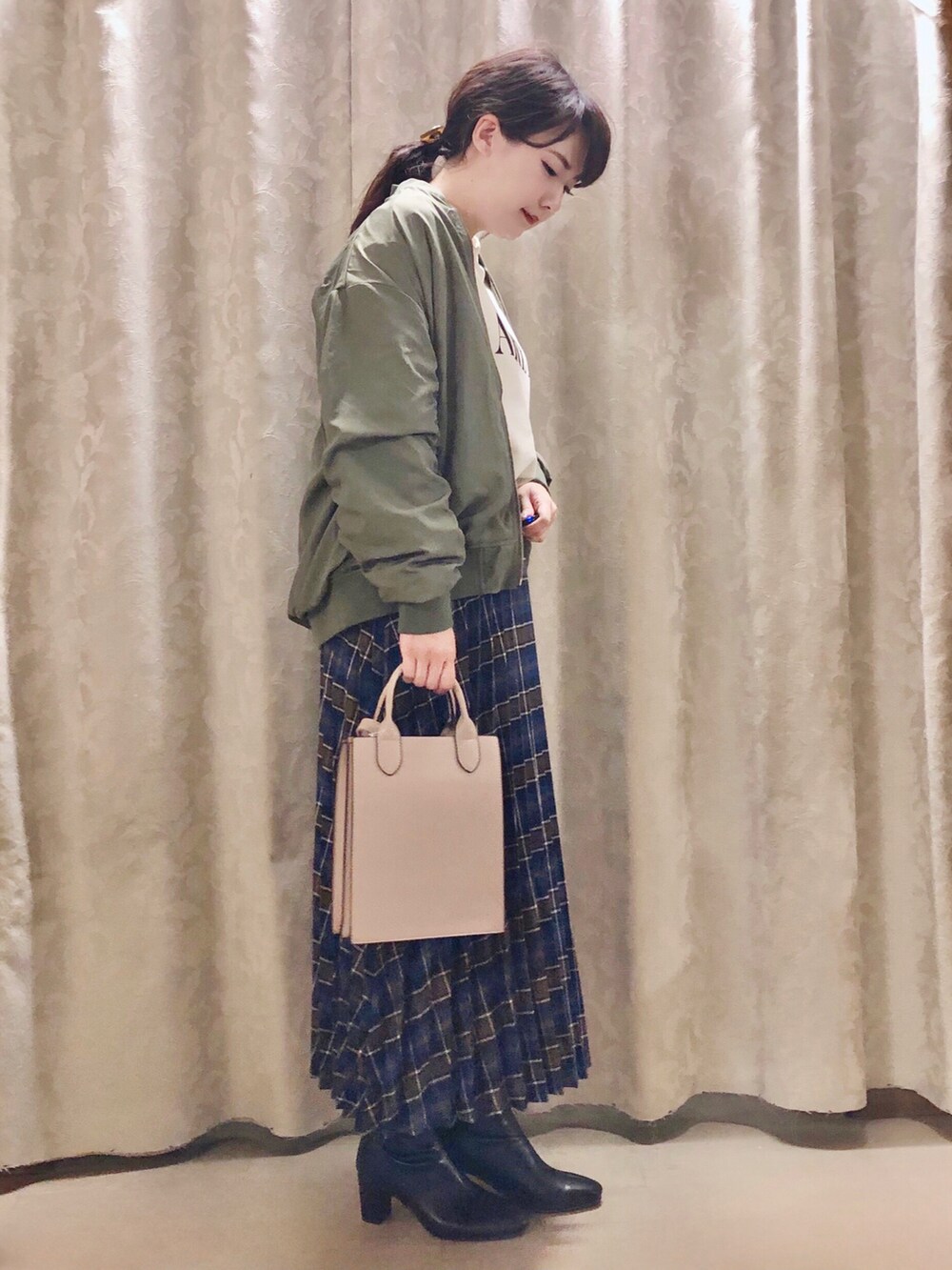 グリーン系のブルゾン、ブルー系のスカート、ブラック系のブーツを着用したレディースの秋コーディネートの2枚目の写真