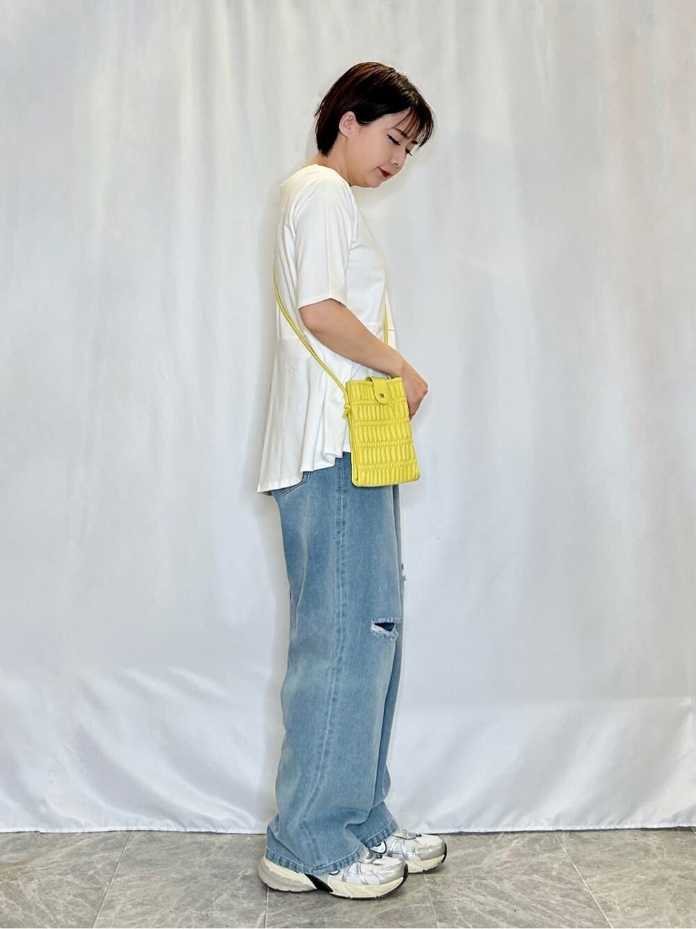 ホワイト系のTシャツ/カットソー、ブルー系のデニムパンツ、イエロー系のショルダーバッグを着用したレディースの春コーディネートの2枚目の写真