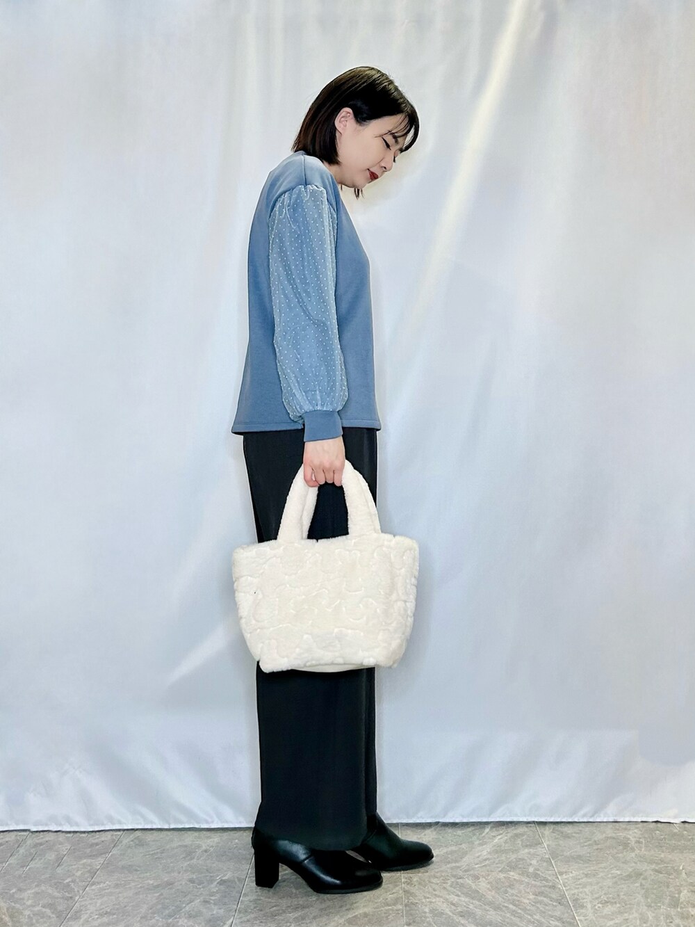 ブルー系のTシャツ/カットソー、ベージュ系のトートバッグ、ブラック系のブーツを着用したレディースの冬コーディネートの2枚目の写真