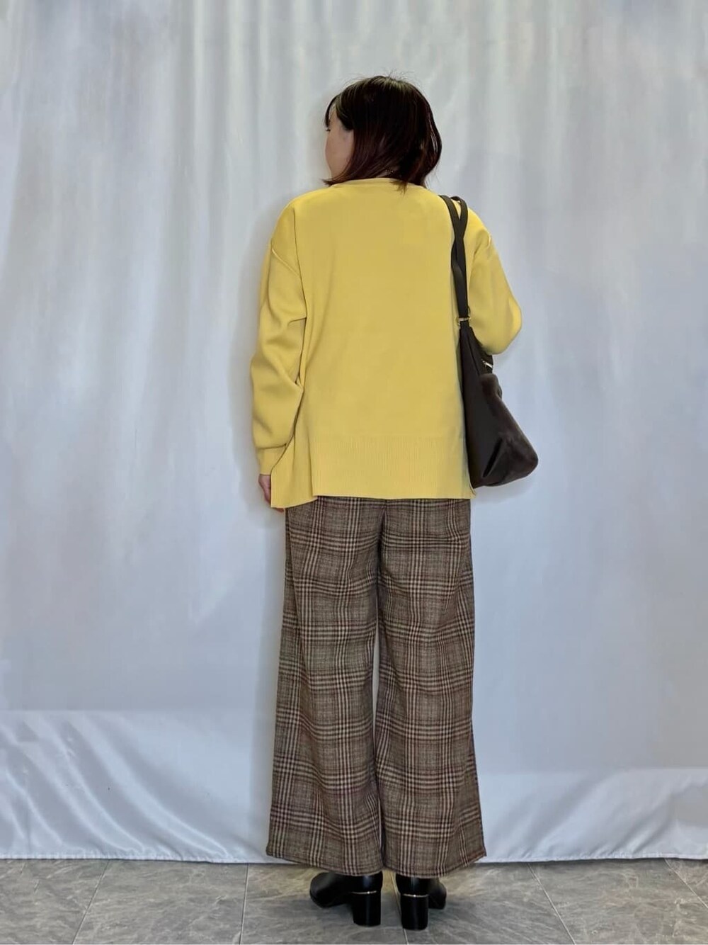 イエロー系のニット/セーター、ブラウン系のその他パンツ、ブラック系のブーツを着用したレディースの冬コーディネートの3枚目の写真