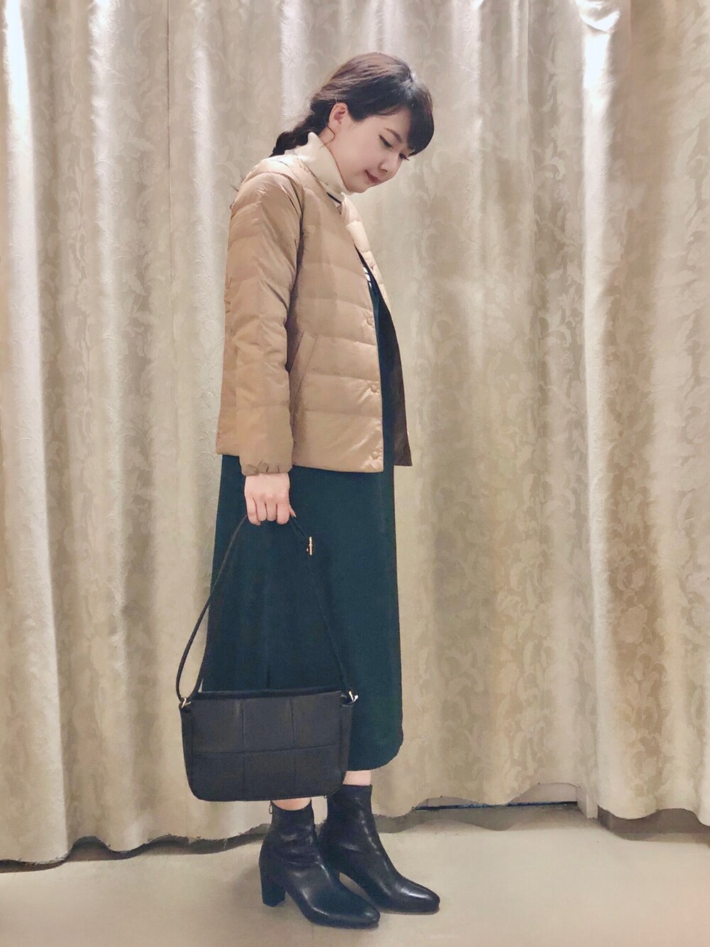 ブラウン系のダウンジャケット/コート、グリーン系のスカート、ホワイト系のニット/セーターを着用したレディースの秋コーディネートの2枚目の写真