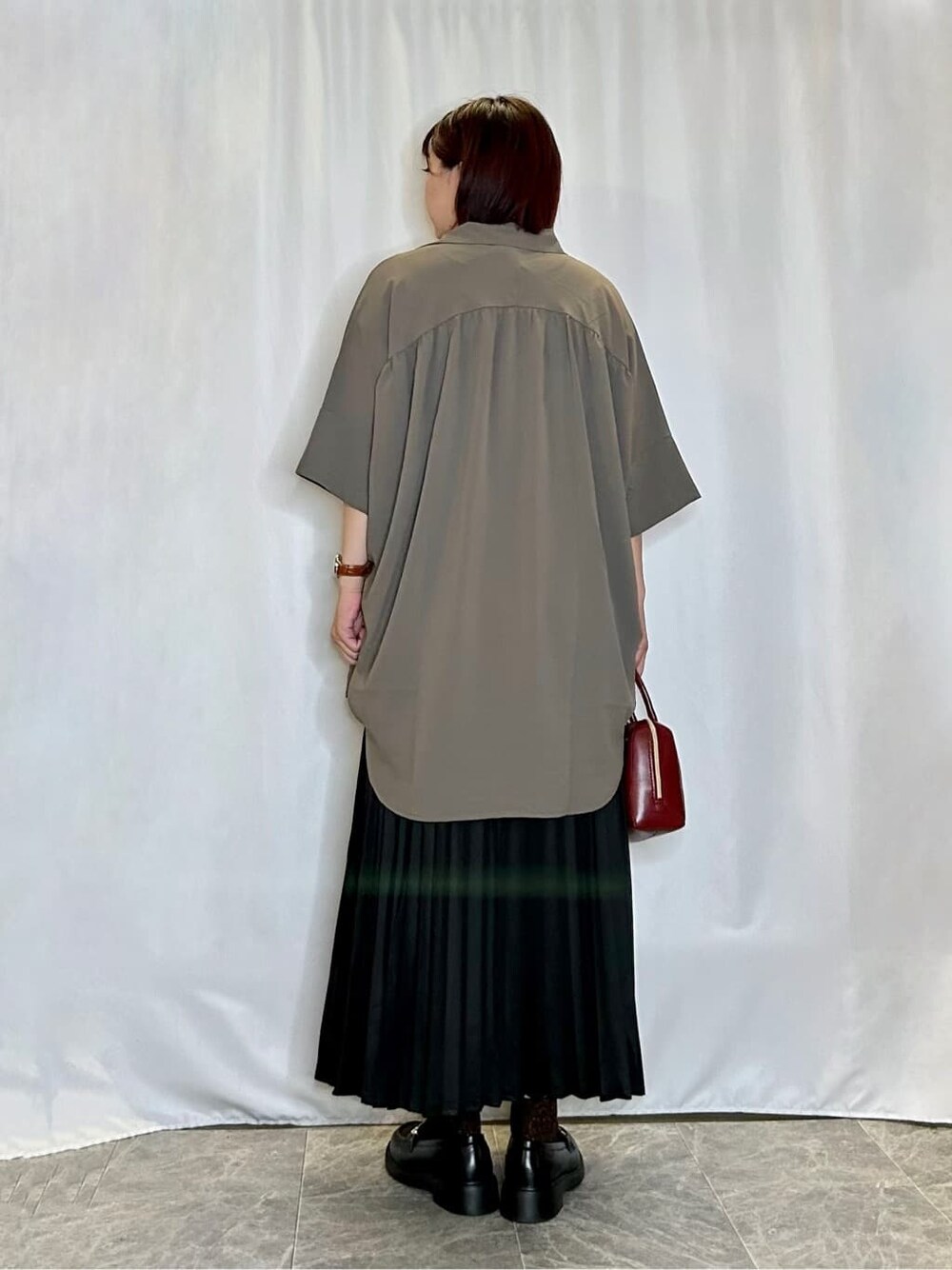 ブラウン系のチュニック、ホワイト系のTシャツ/カットソー、ブラック系のスカートを着用したレディースの夏コーディネートの3枚目の写真