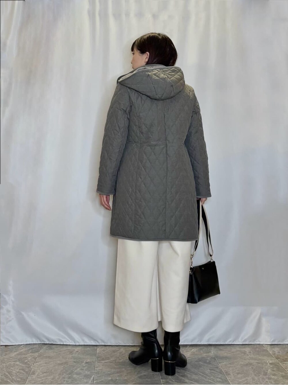 グレー系のその他アウター、ブラック系のニット/セーター、ホワイト系のその他パンツを着用したレディースの冬コーディネートの3枚目の写真