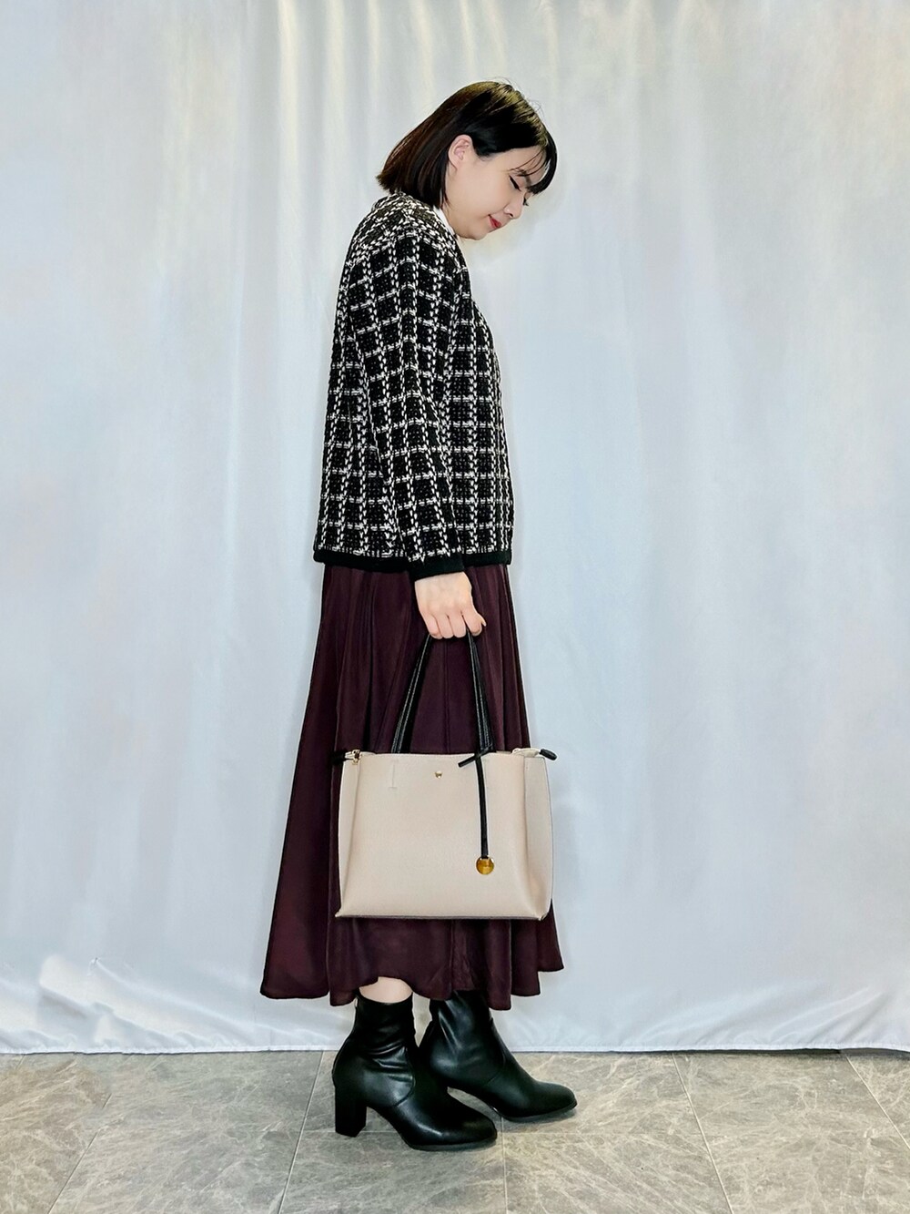 ブラウン系のスカート、ベージュ系のトートバッグ、ブラック系のブーツを着用したレディースの秋コーディネートの2枚目の写真