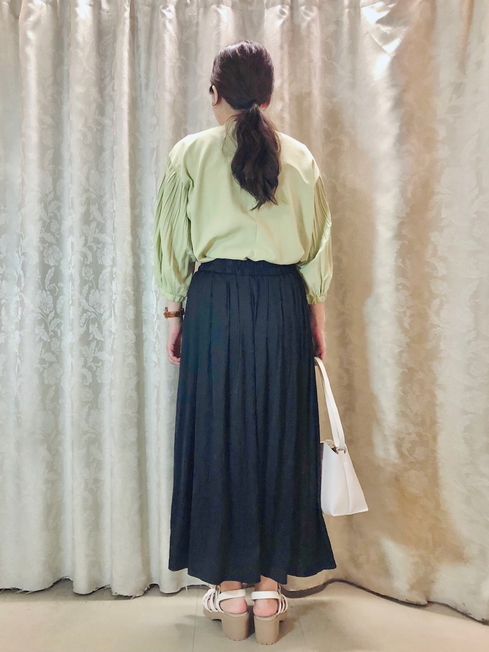 グリーン系のシャツ/ブラウス、ブルー系のスカート、ホワイト系のショルダーバッグを着用したレディースの春コーディネートの3枚目の写真